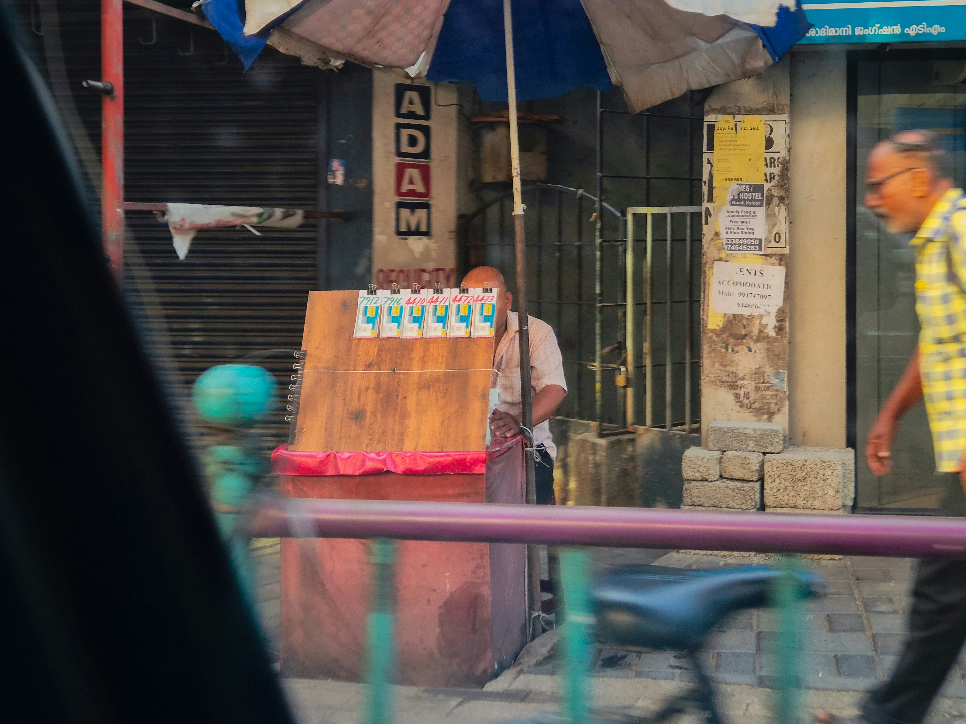 Street vendor selling bottled water under an umbrella.