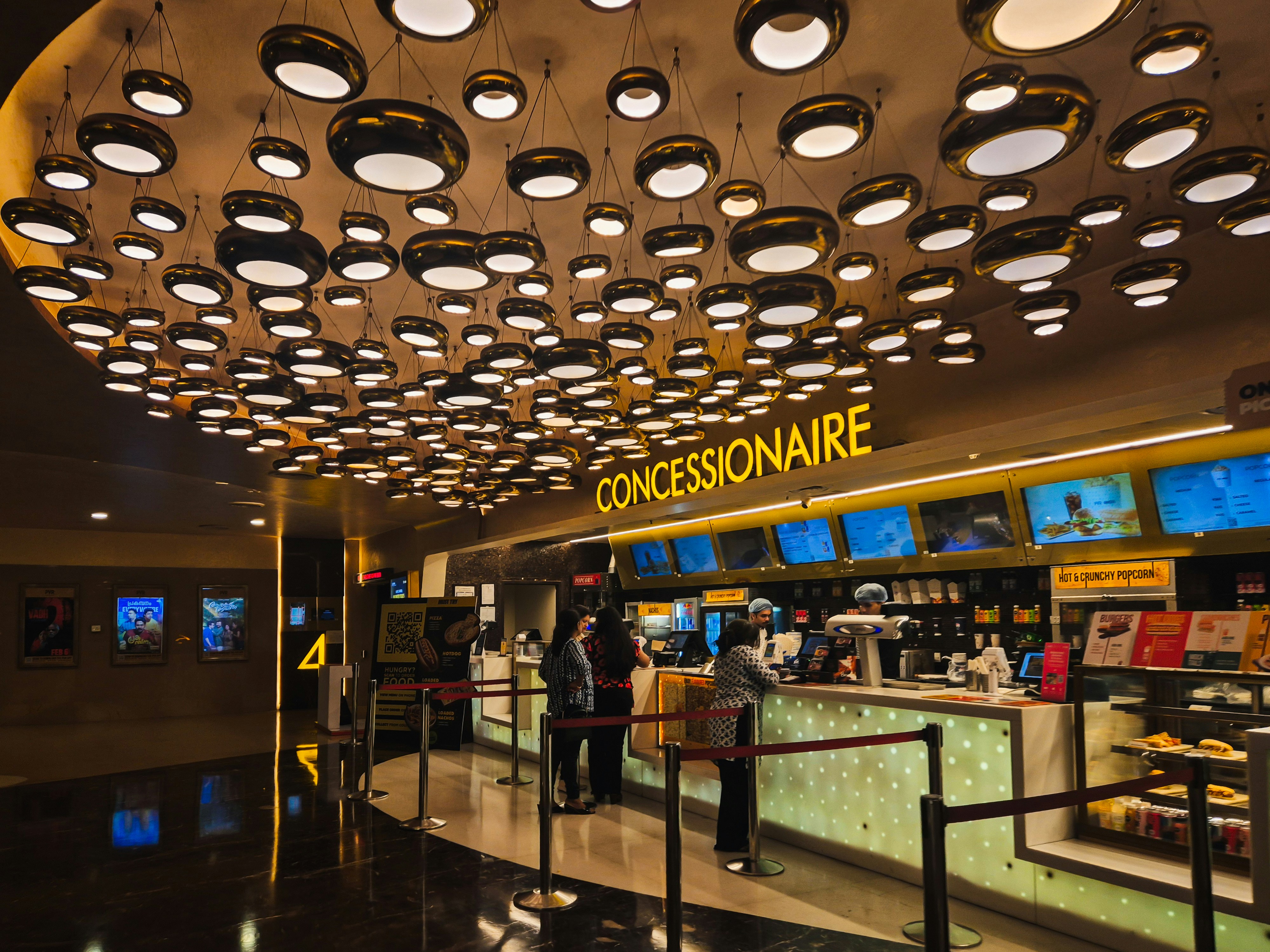 People at a brightly lit concession stand in a cinema.
