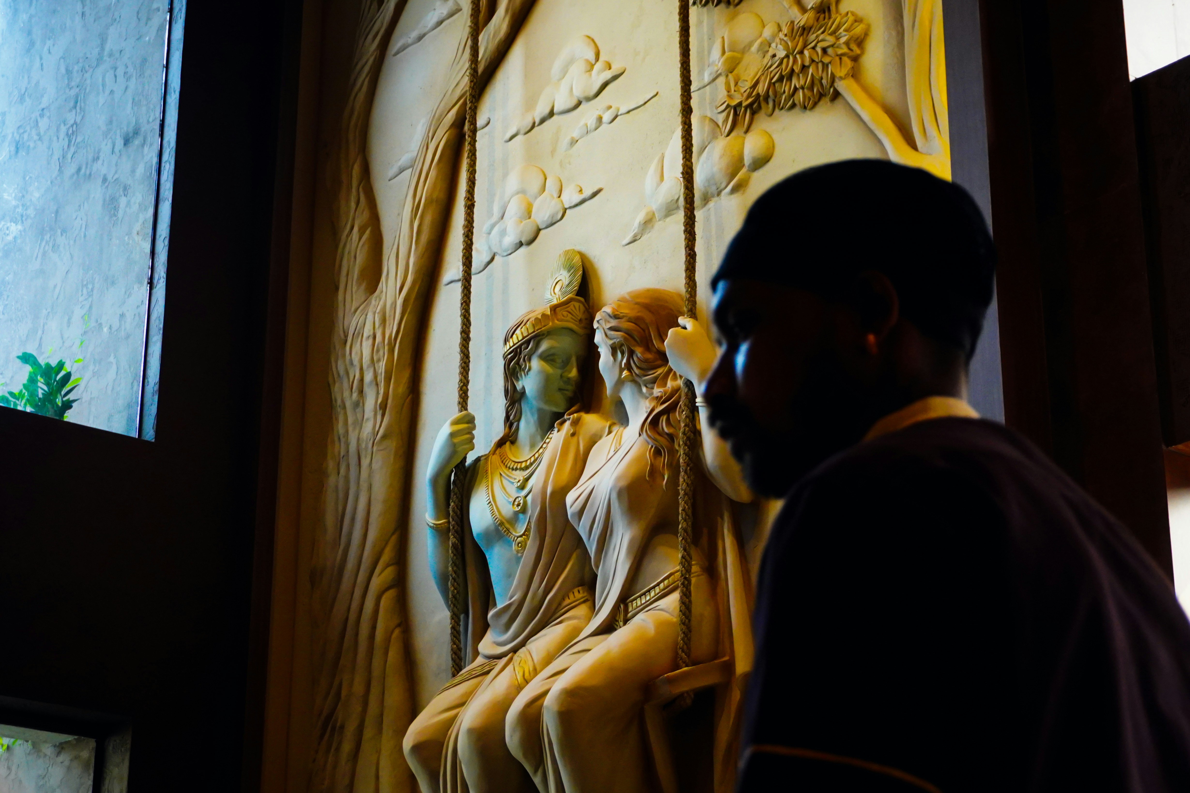 Mann betrachtet das gemeißelte Relief von drei Figuren auf der Schaukel