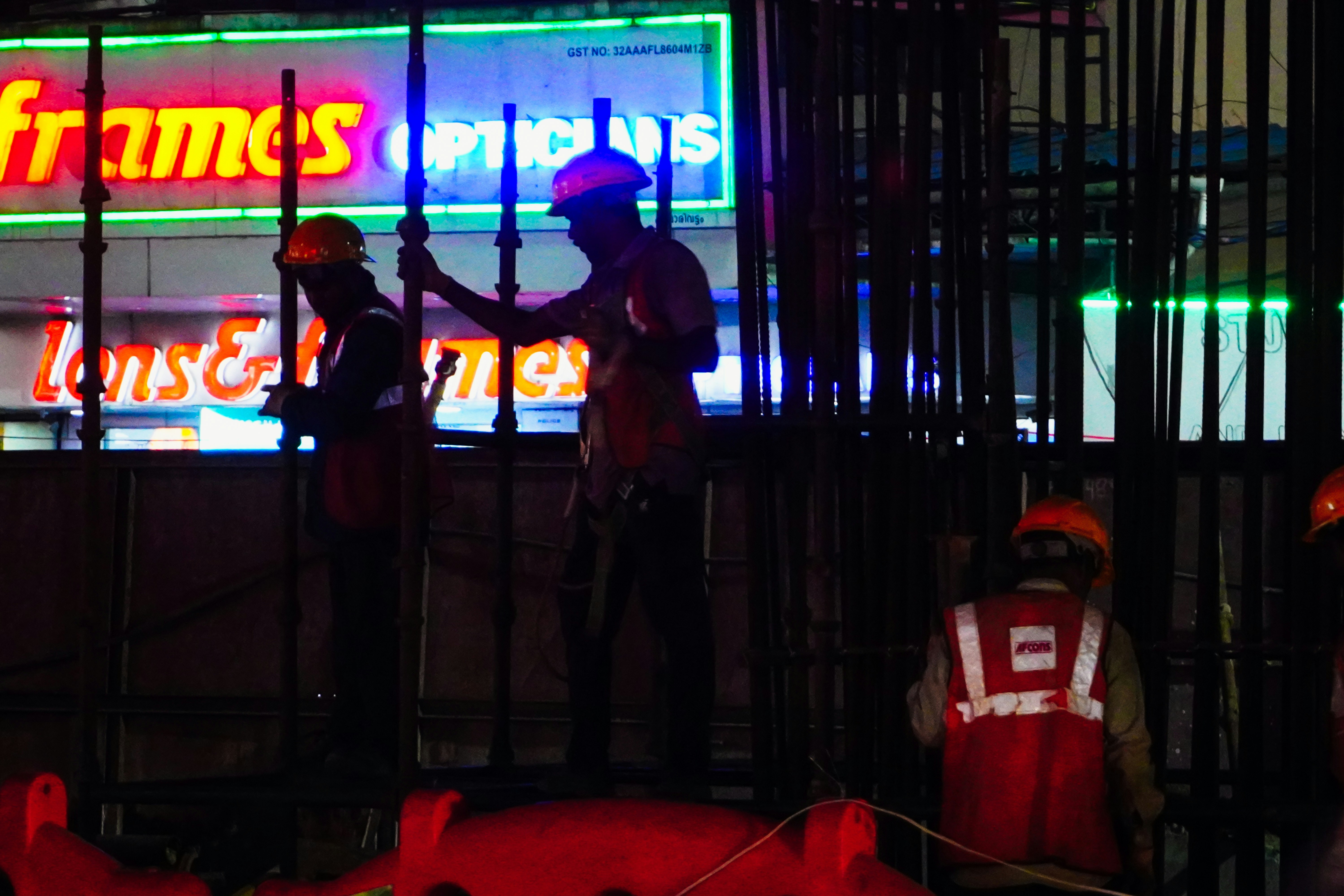 Workers in orange vests and hard hats at night