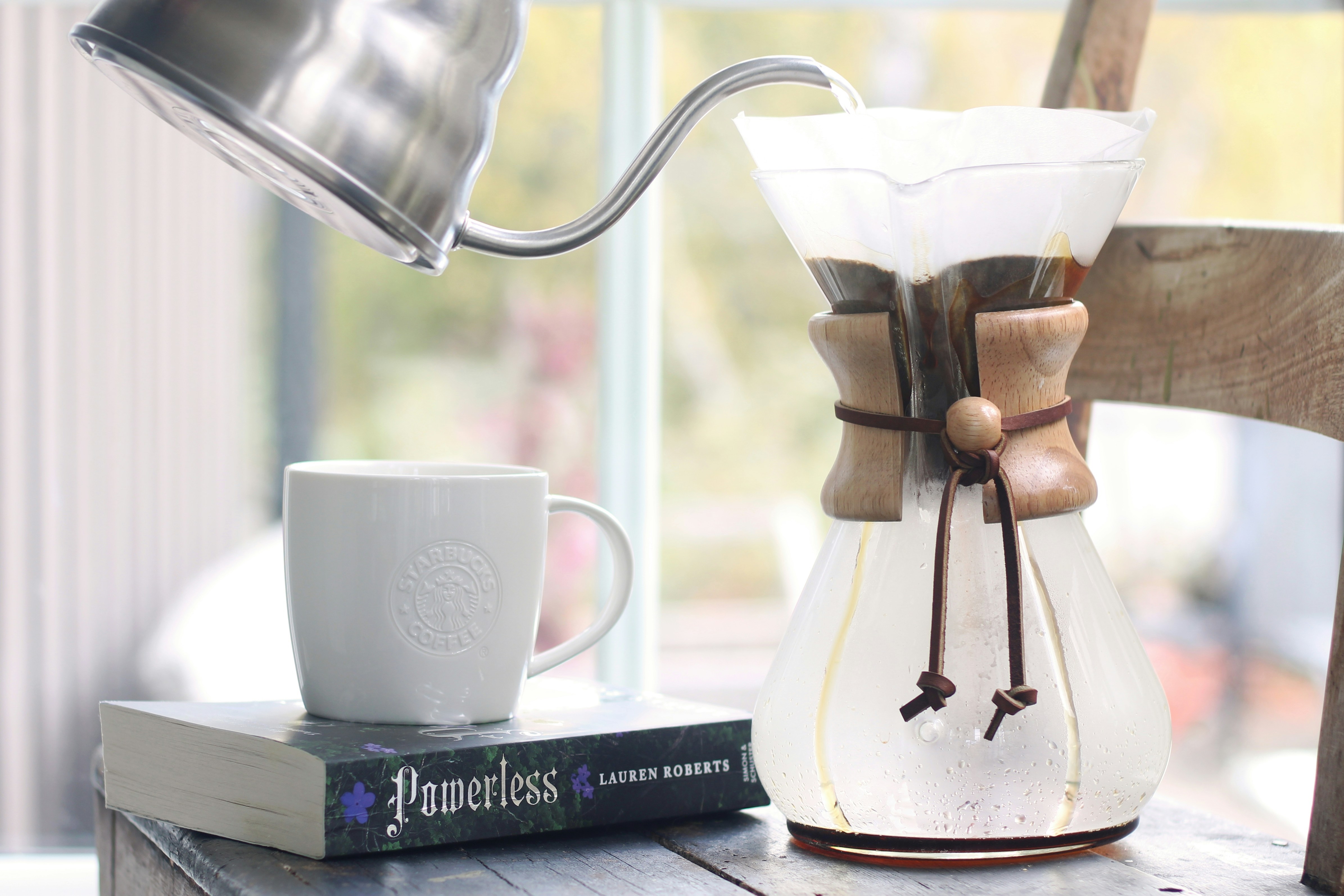 Verser de l’eau dans une cafetière Chemex près de la fenêtre.