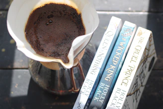 Pour-over coffee brewing next to three books.