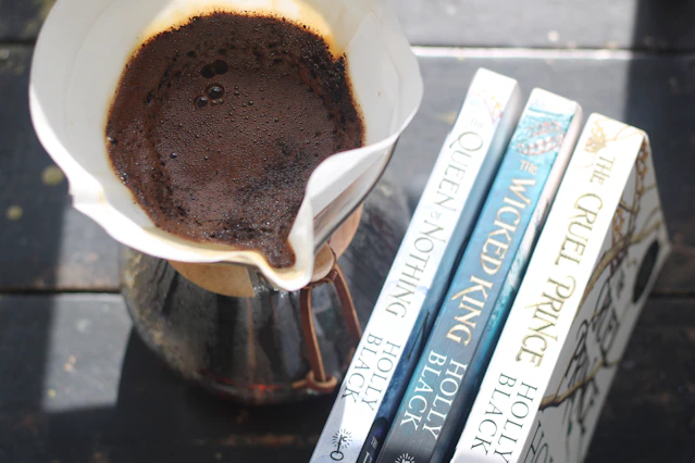 Pour-over coffee brewing next to three books.