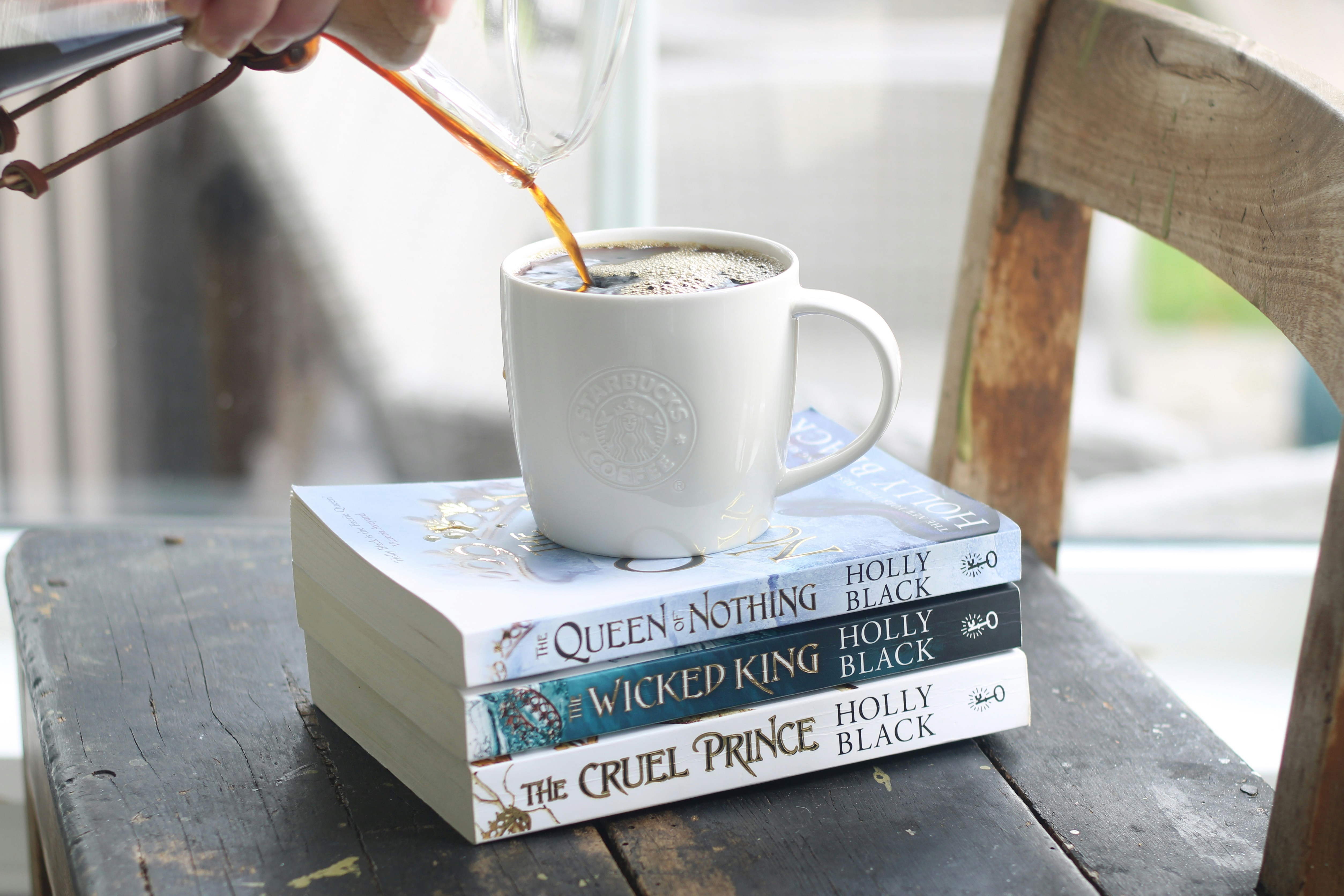 Du café versé dans une tasse sur une pile de livres