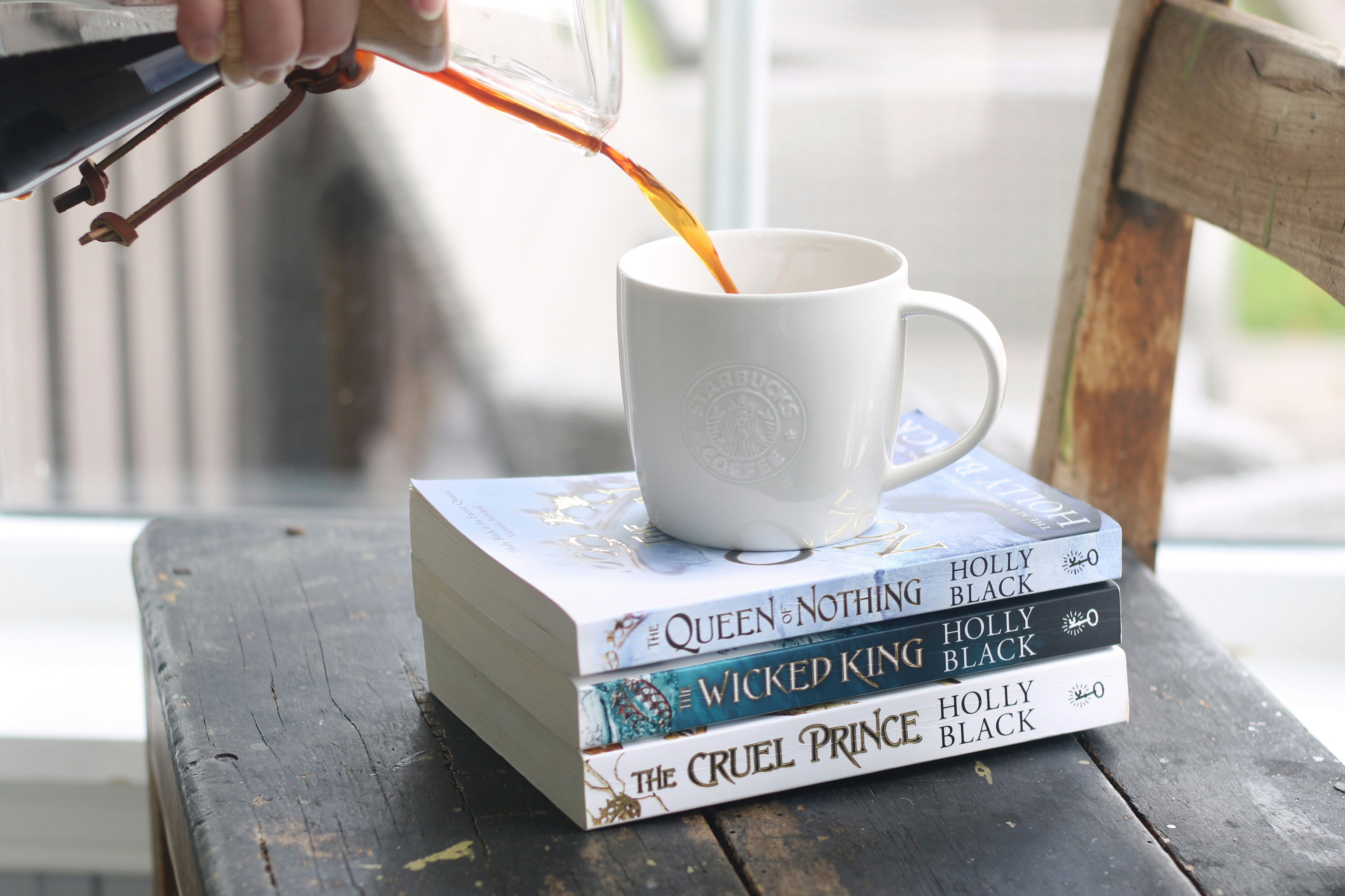 Du café versé dans une tasse sur des livres empilés.