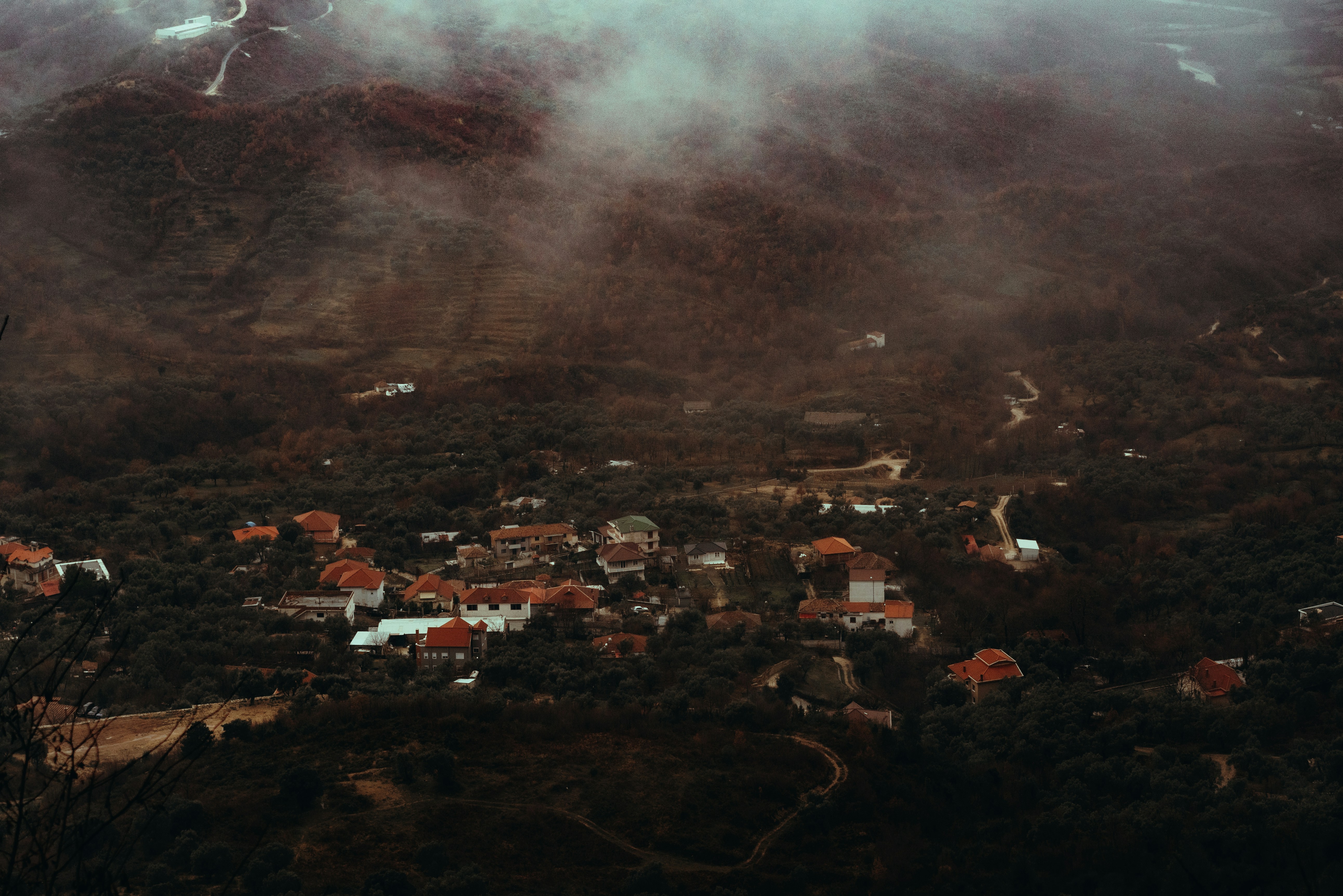 A village nestled among misty, dark green hills.