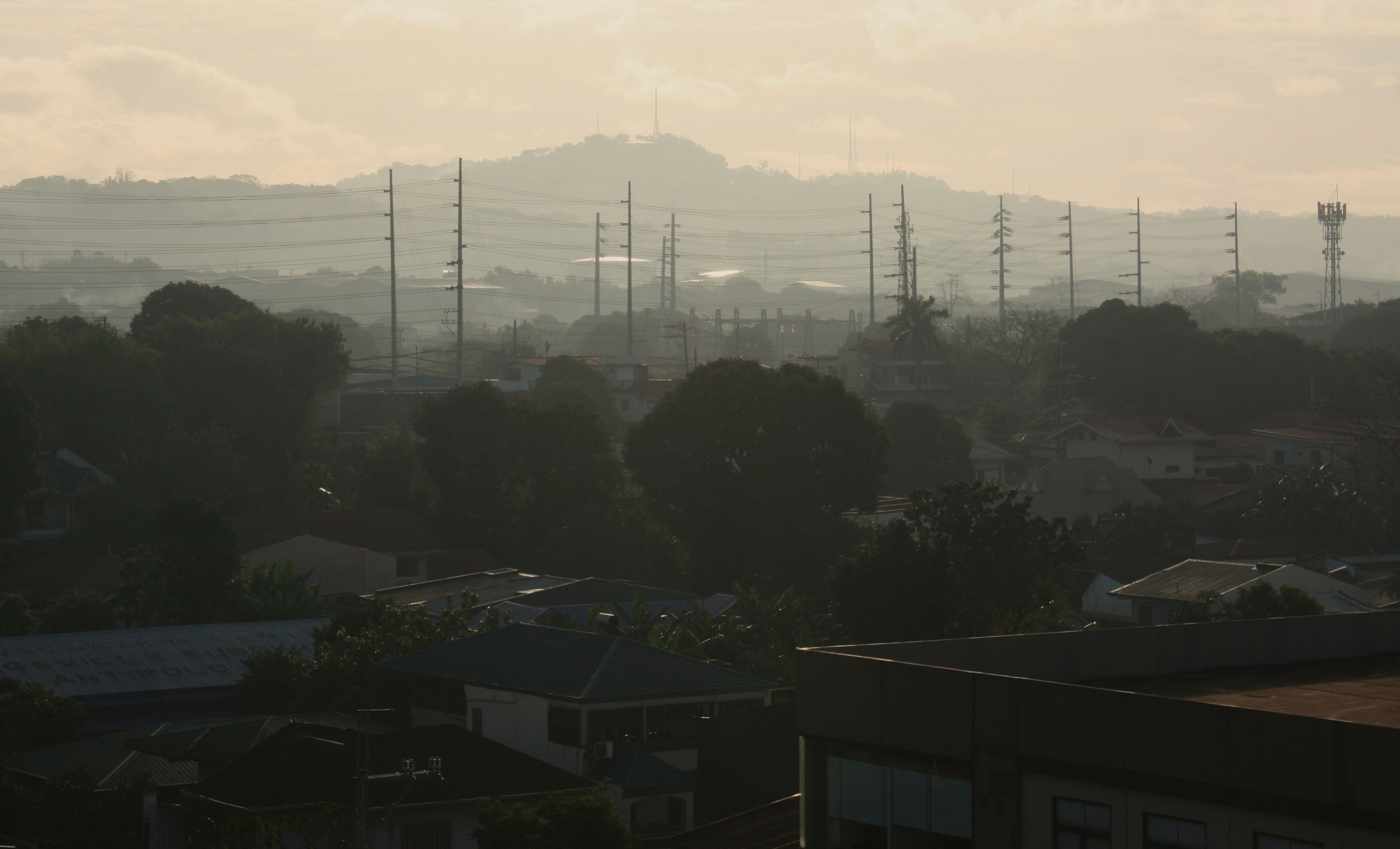 Misty morning cityscape with distant hills and towers.