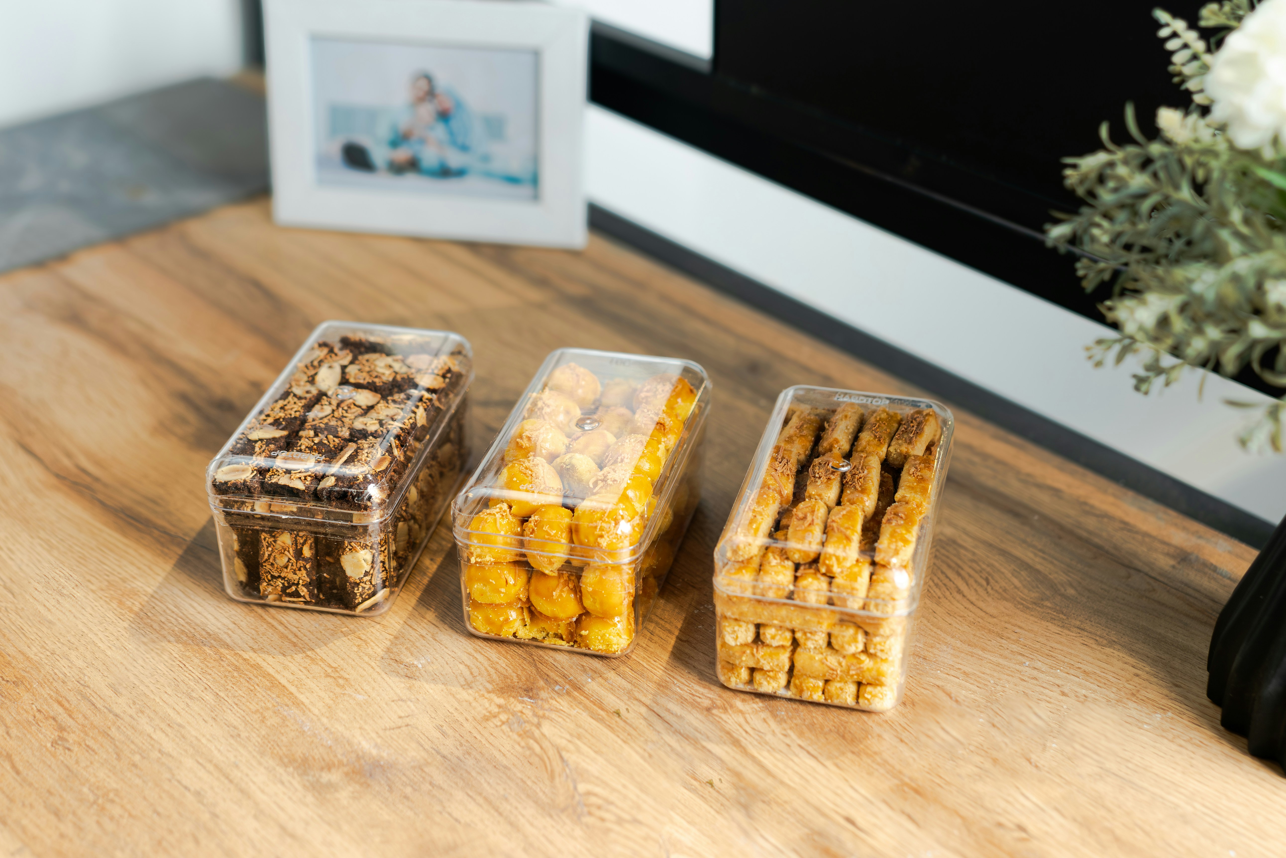 Three clear boxes filled with cookies on a wooden table.
