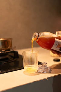 Juice being poured from bottle into glass with ice cubes