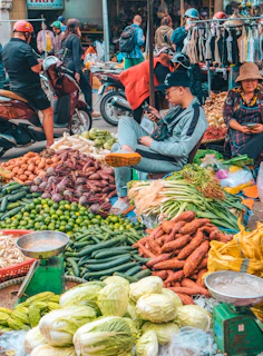 Busy outdoor market with fresh produce and people.