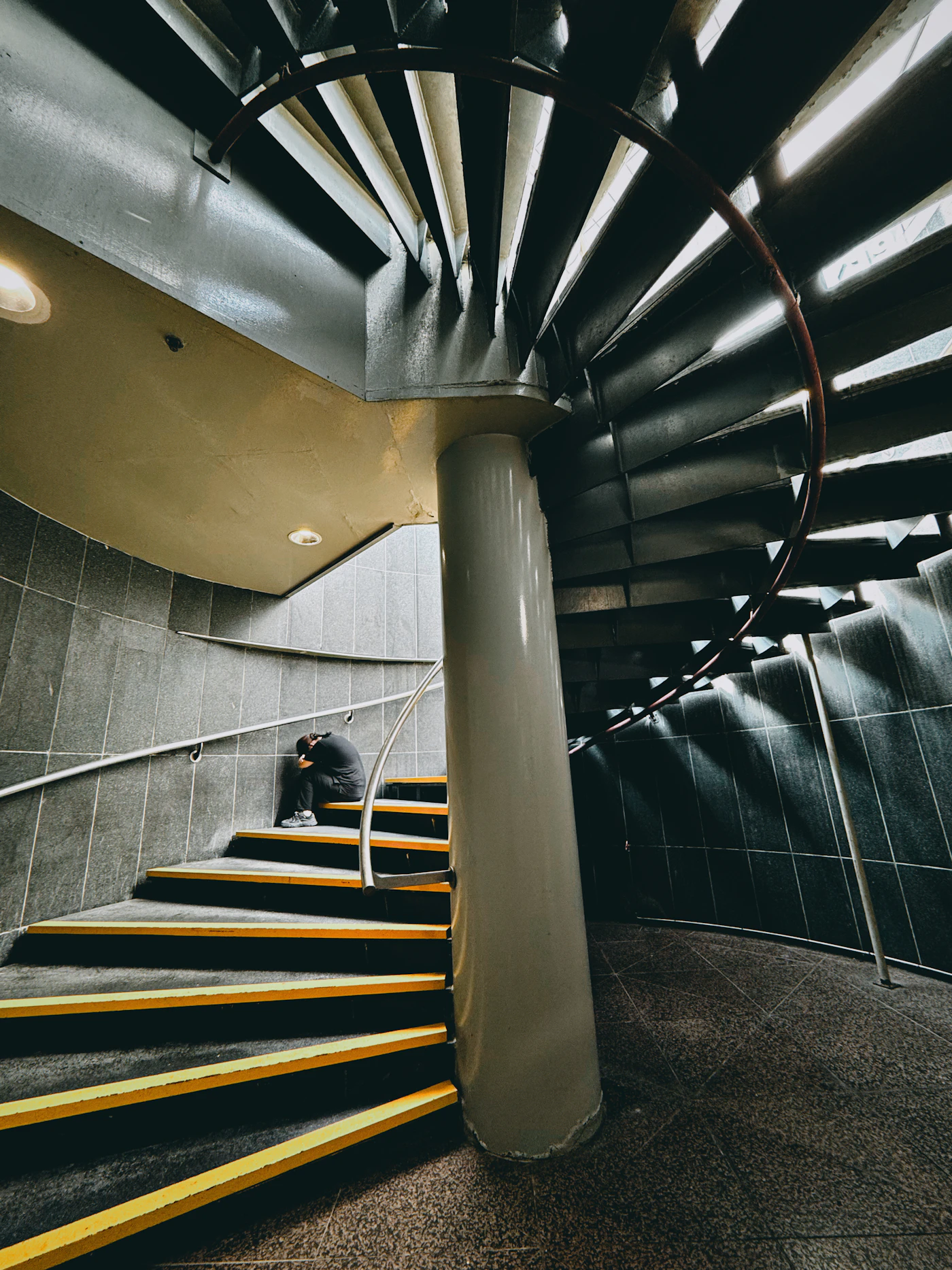 A person sitting alone on a spiral staircase