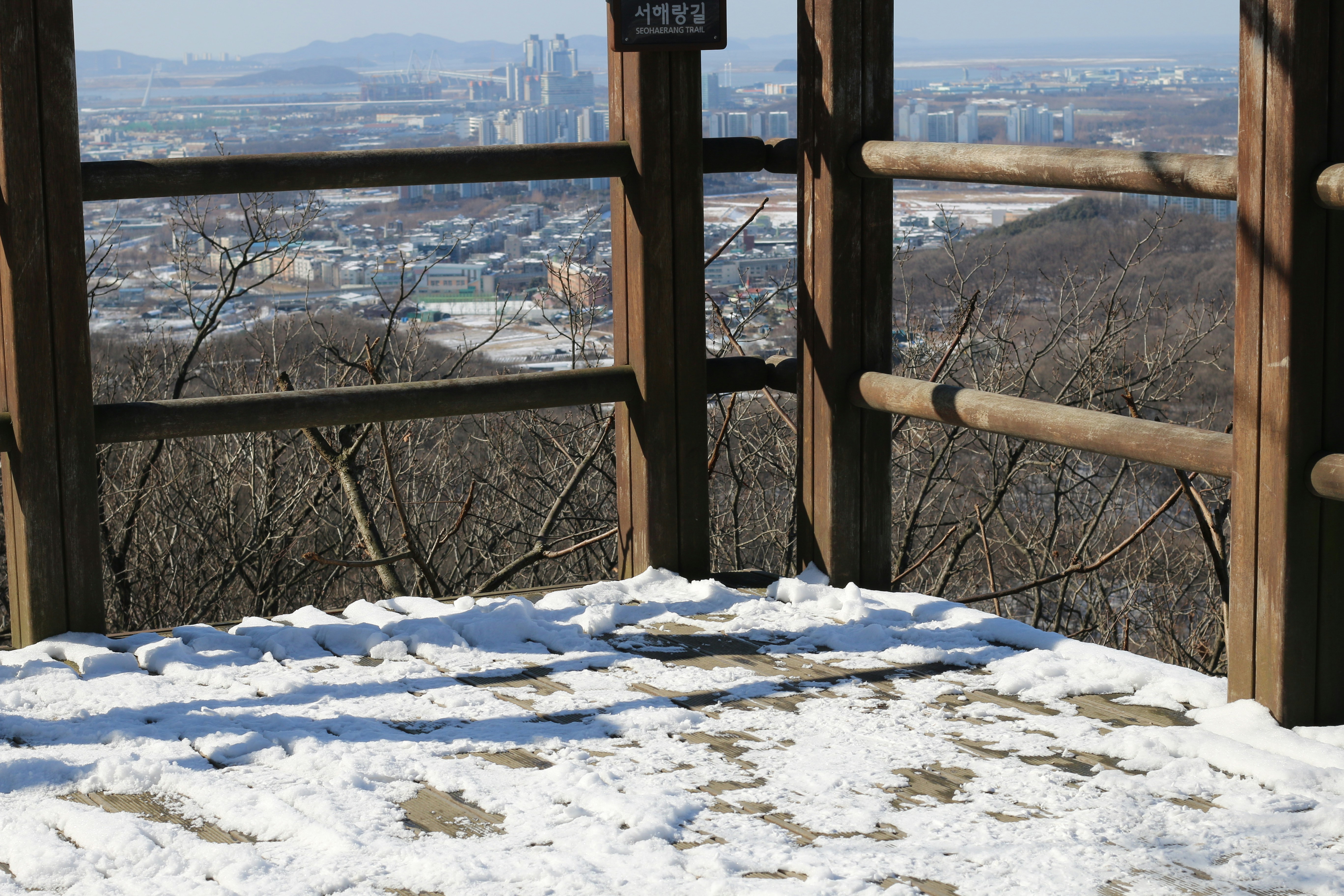Wooden viewpoint overlooking a snow-dusted city landscape