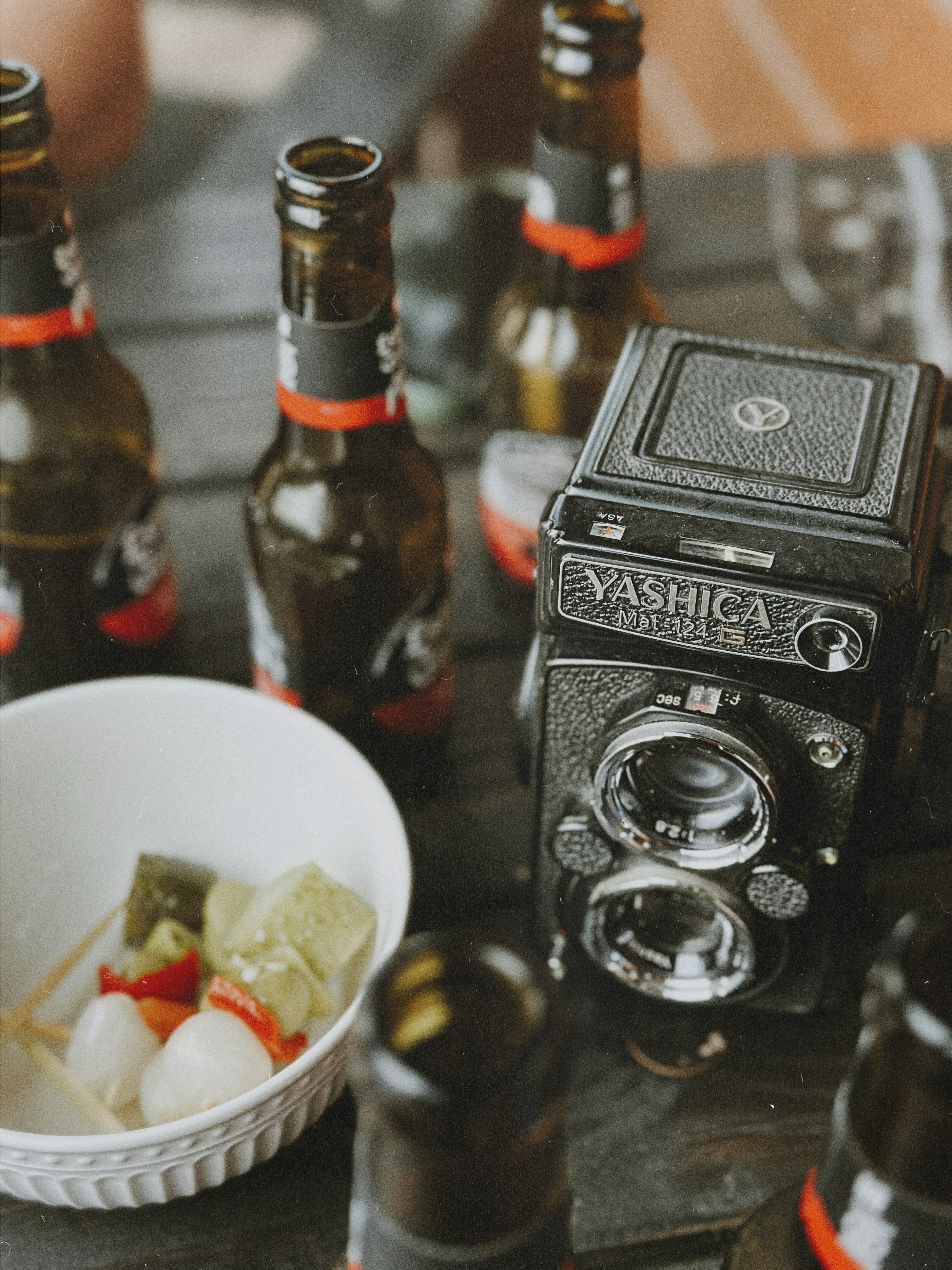 Bottles of beer and a vintage camera on a table.