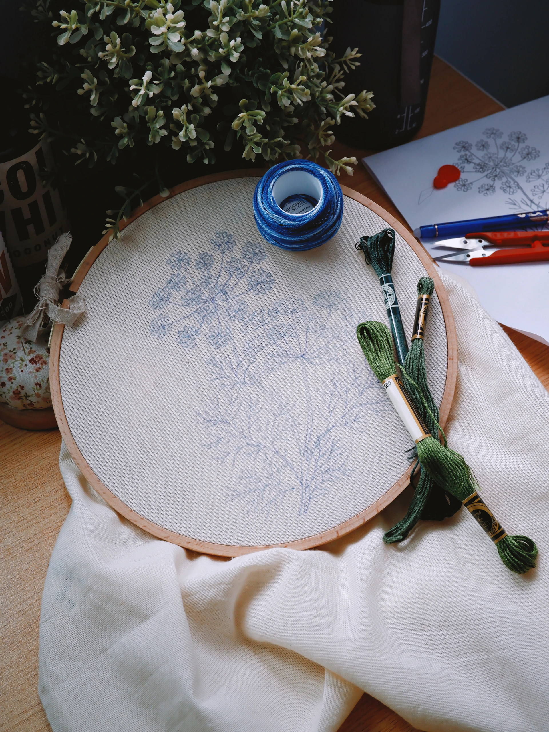 Embroidery hoop with dill pattern and green threads.