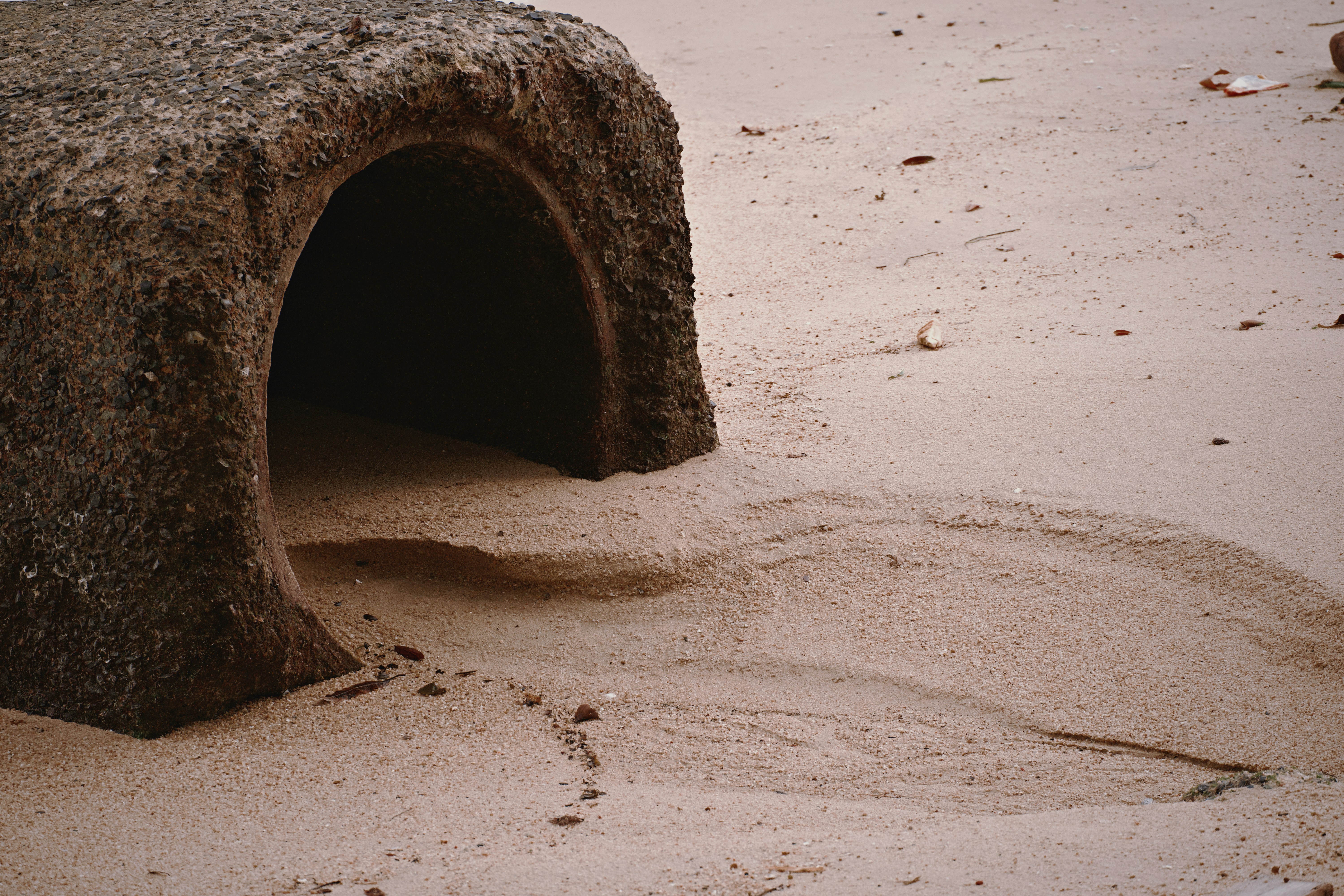 A dark cave entrance in a sandy landscape