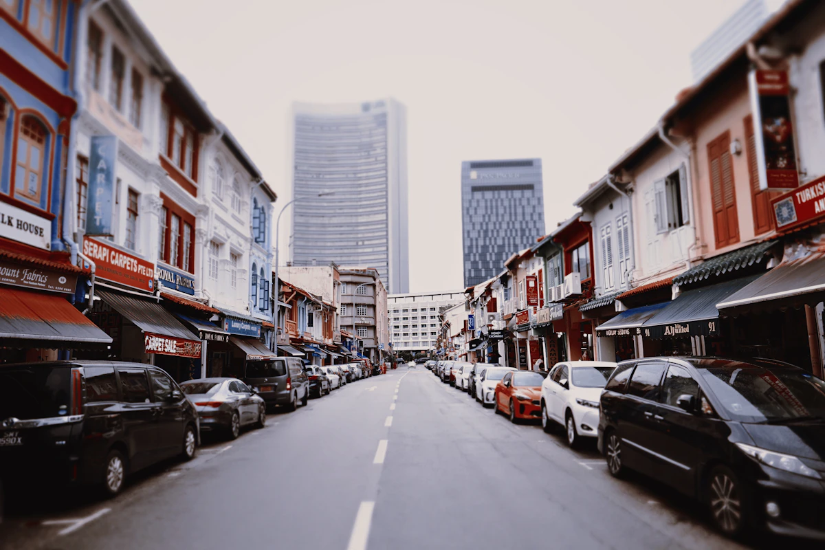 Jalan dengan deretan bangunan berwarna-warni dan mobil terparkir