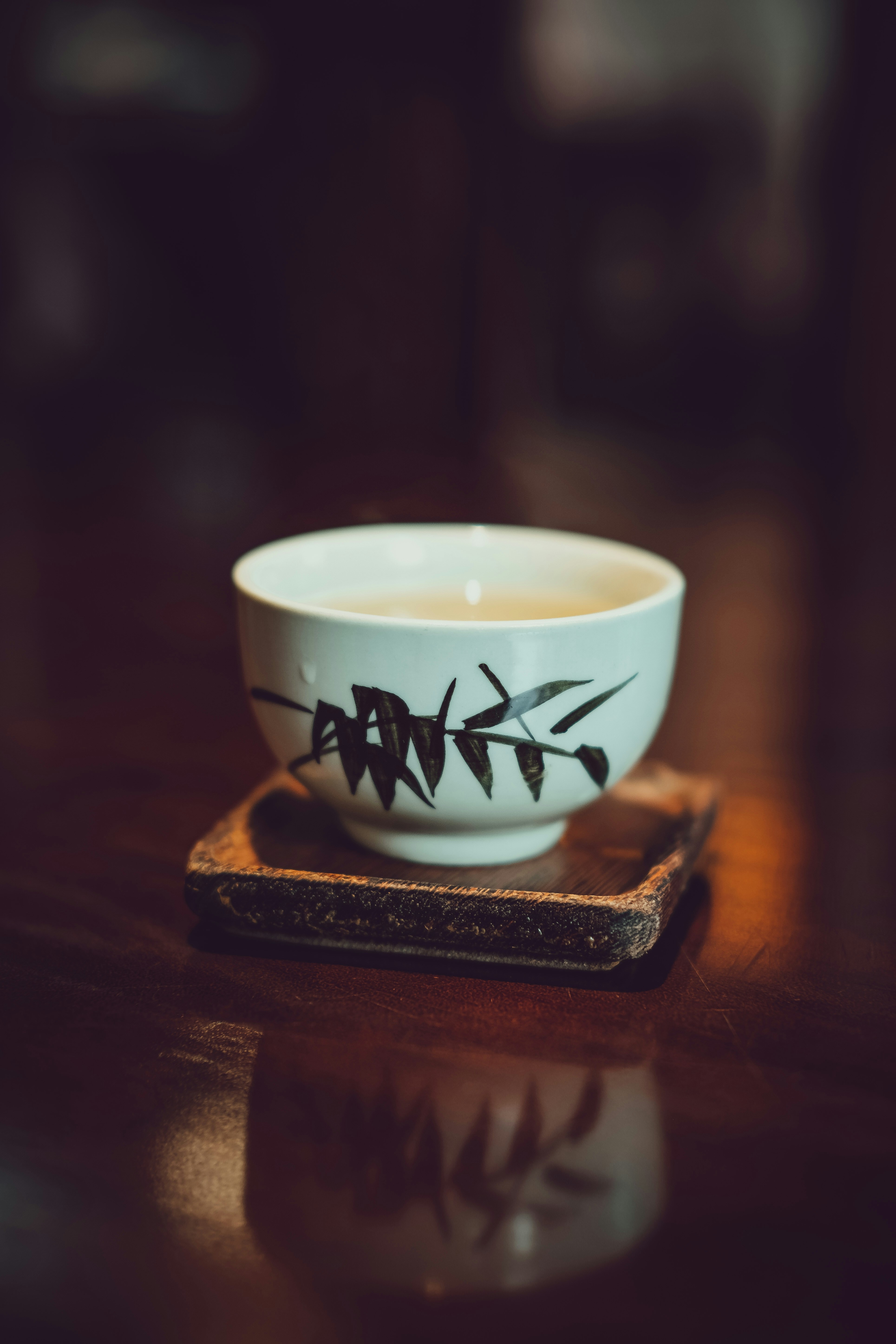 A white teacup with bamboo design on coaster.
