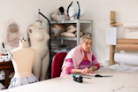 Woman working at a sewing table with mannequins.