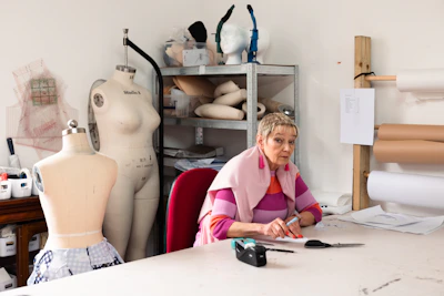 Woman working at a sewing table with mannequins.