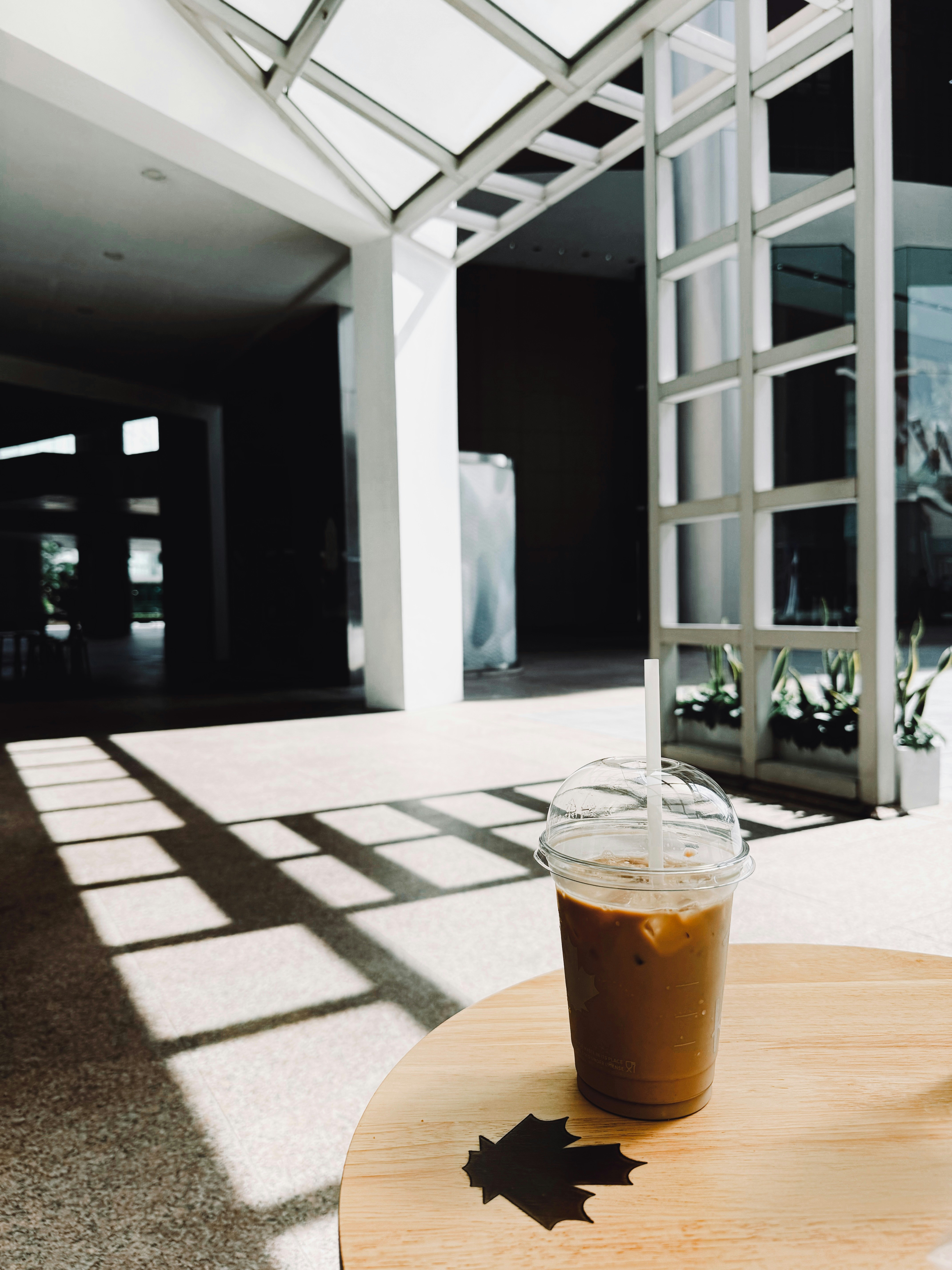 Caffè freddo su un tavolo con un'ombra di foglie.