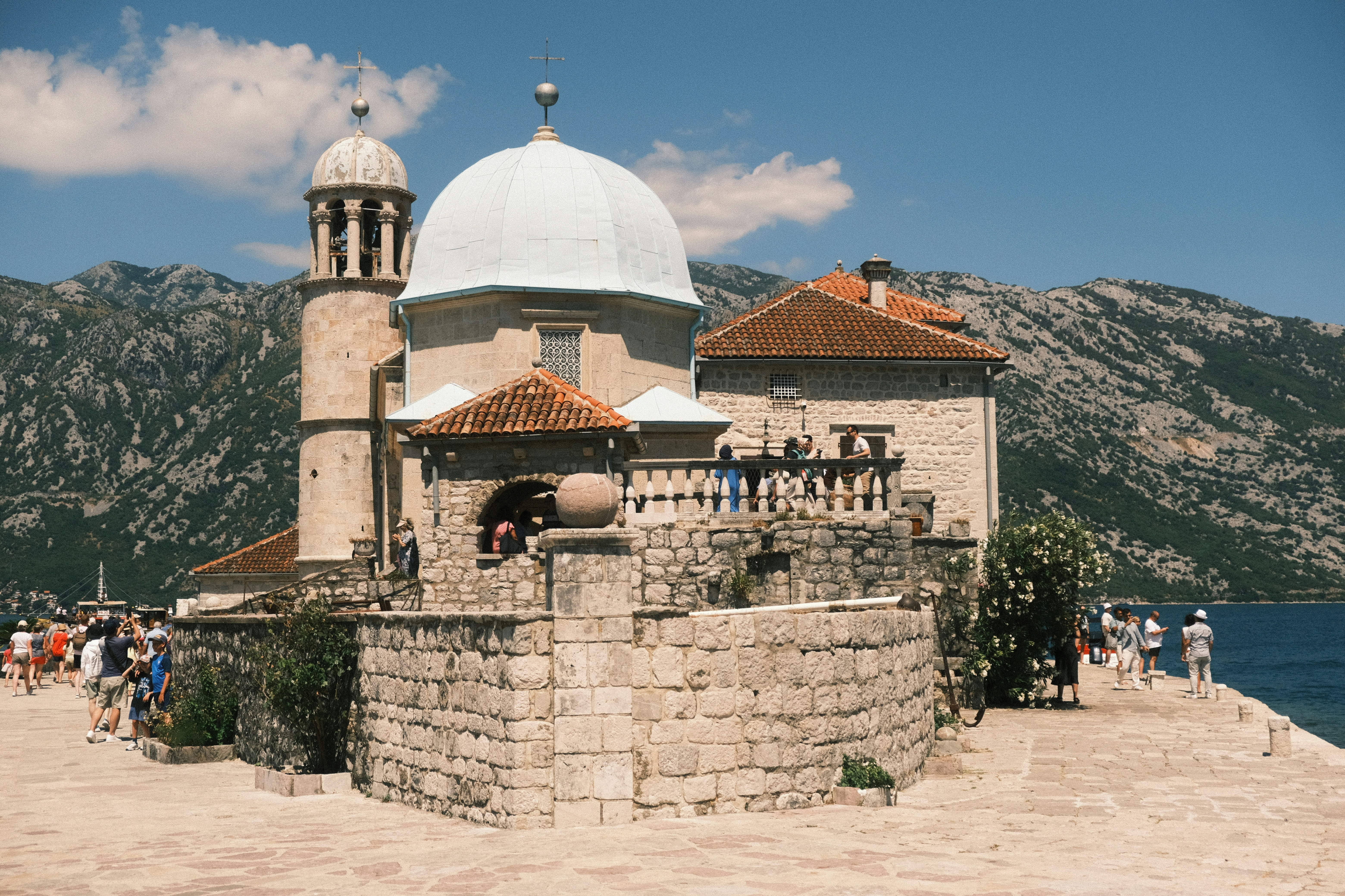 Island church with dome and bell tower near mountains