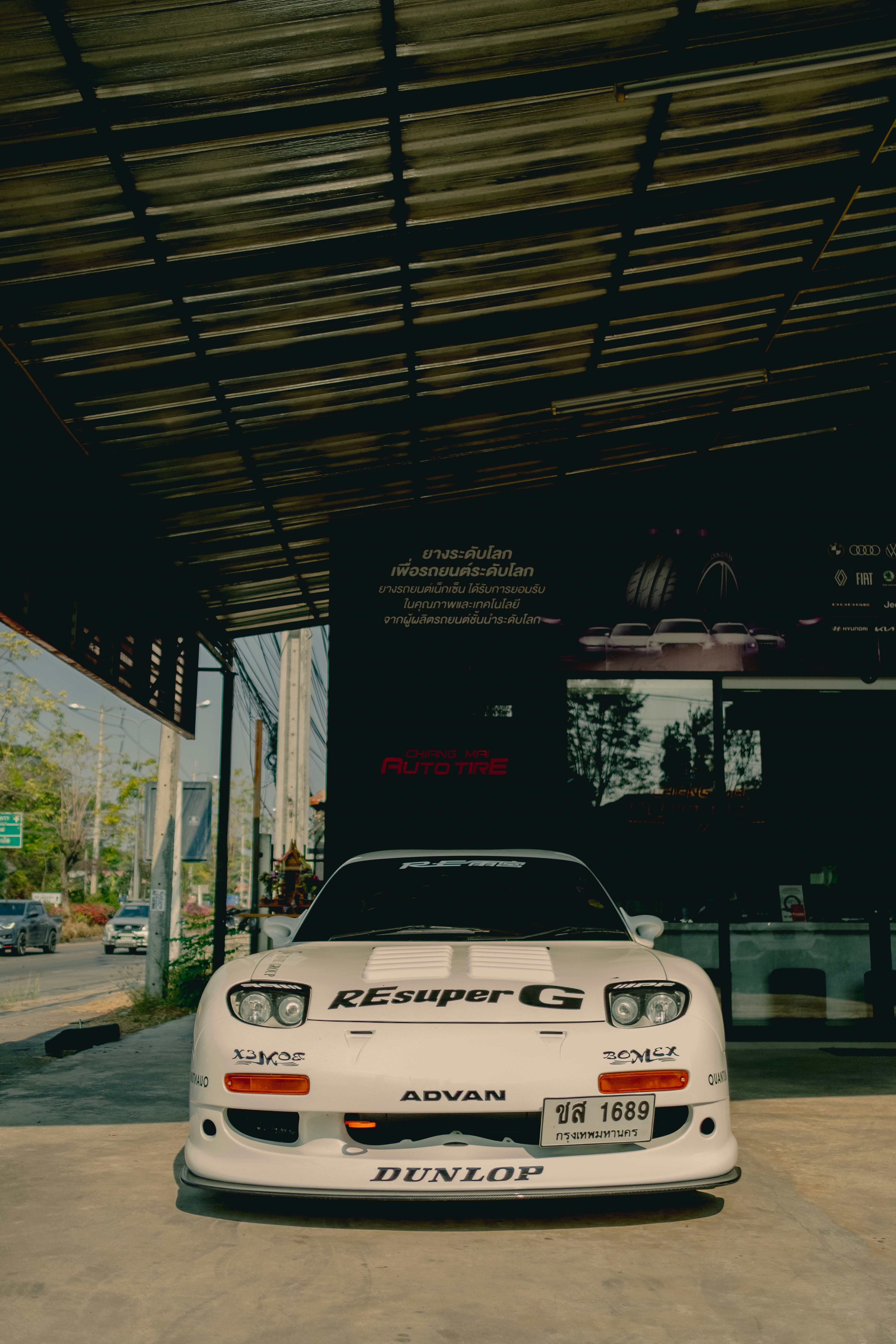 White sports car with racing decals parked outside.