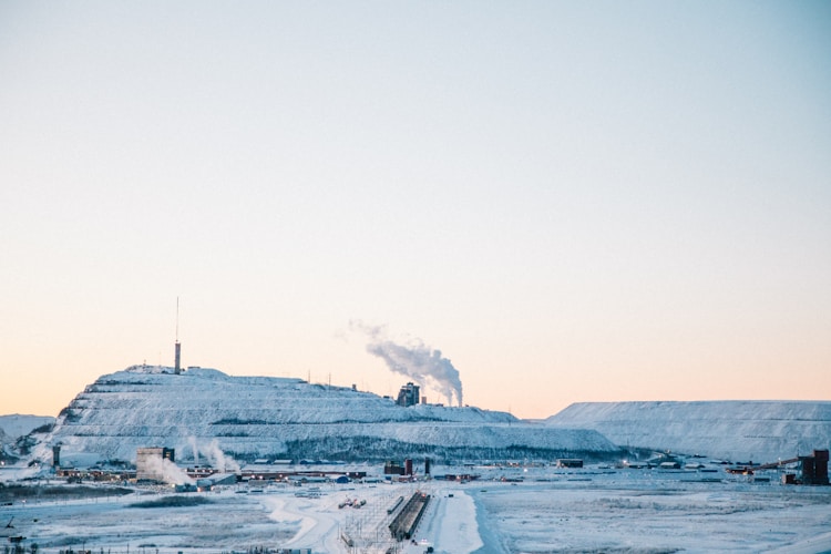 Industrial mining site against a snow-covered hillside, illustrating the environmental scale of resource extraction