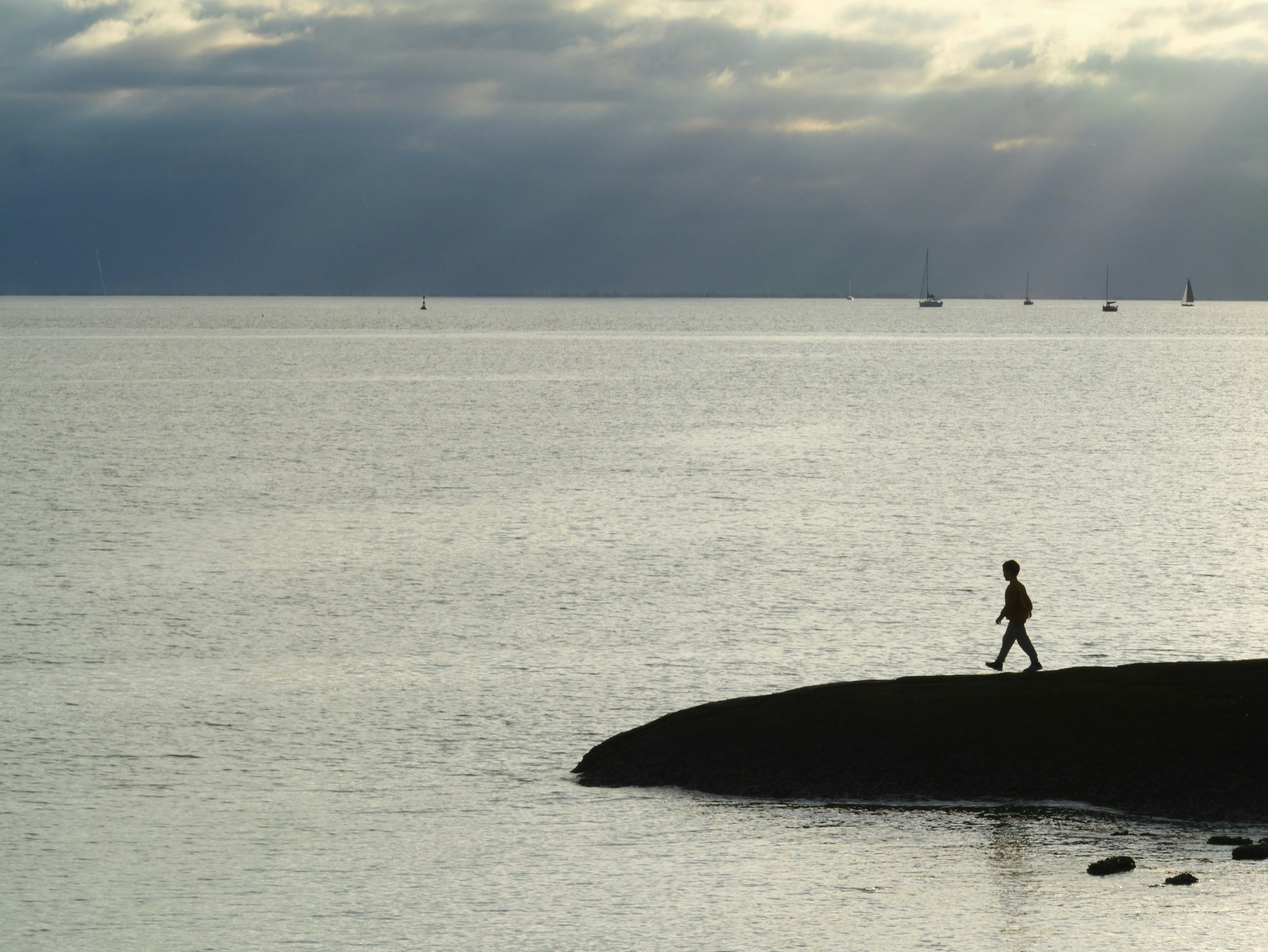 Une personne marche le long d’un rivage rocheux au bord de l’océan.