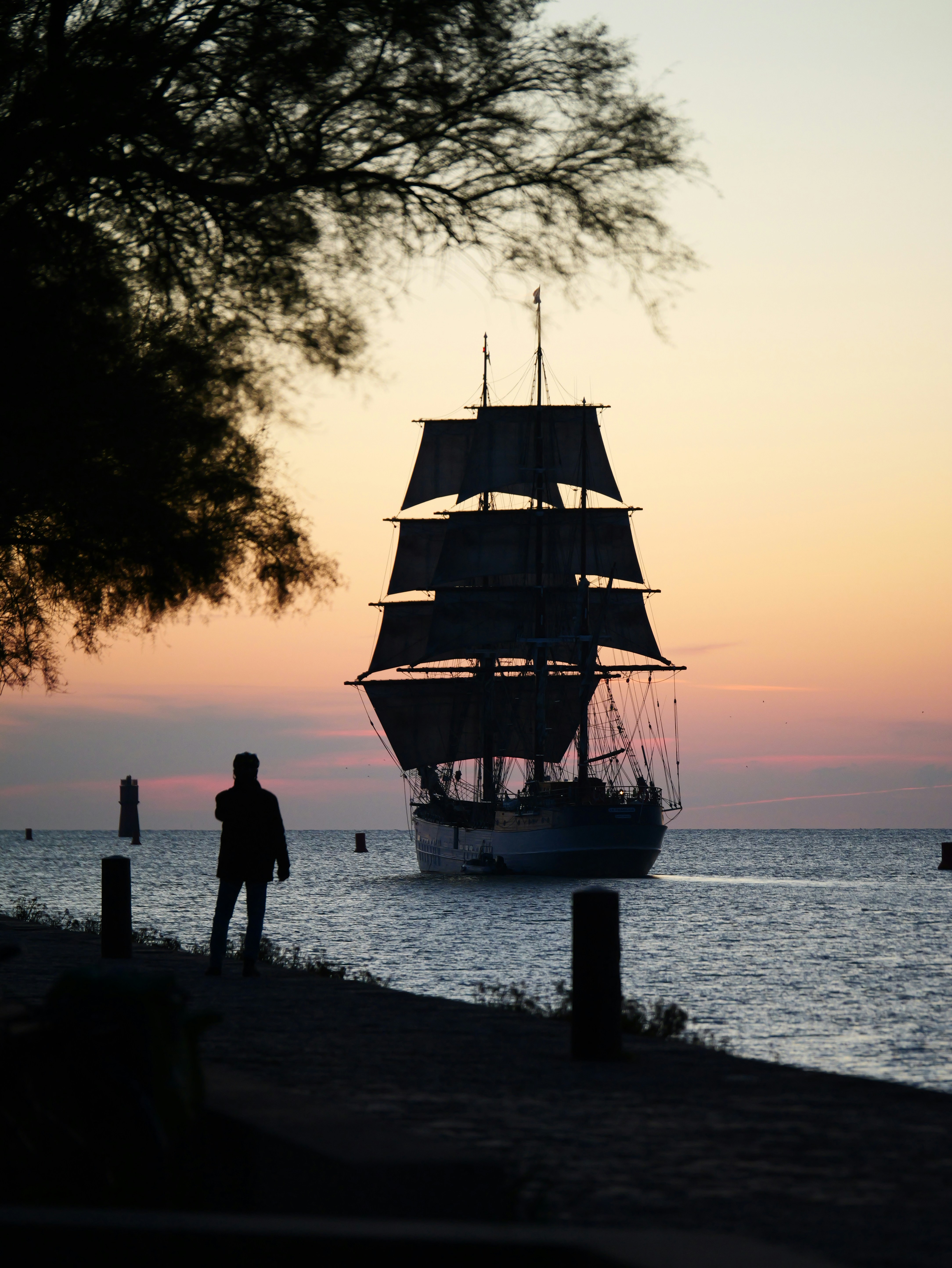 Un grand voilier navigue sur l’océan au coucher du soleil.