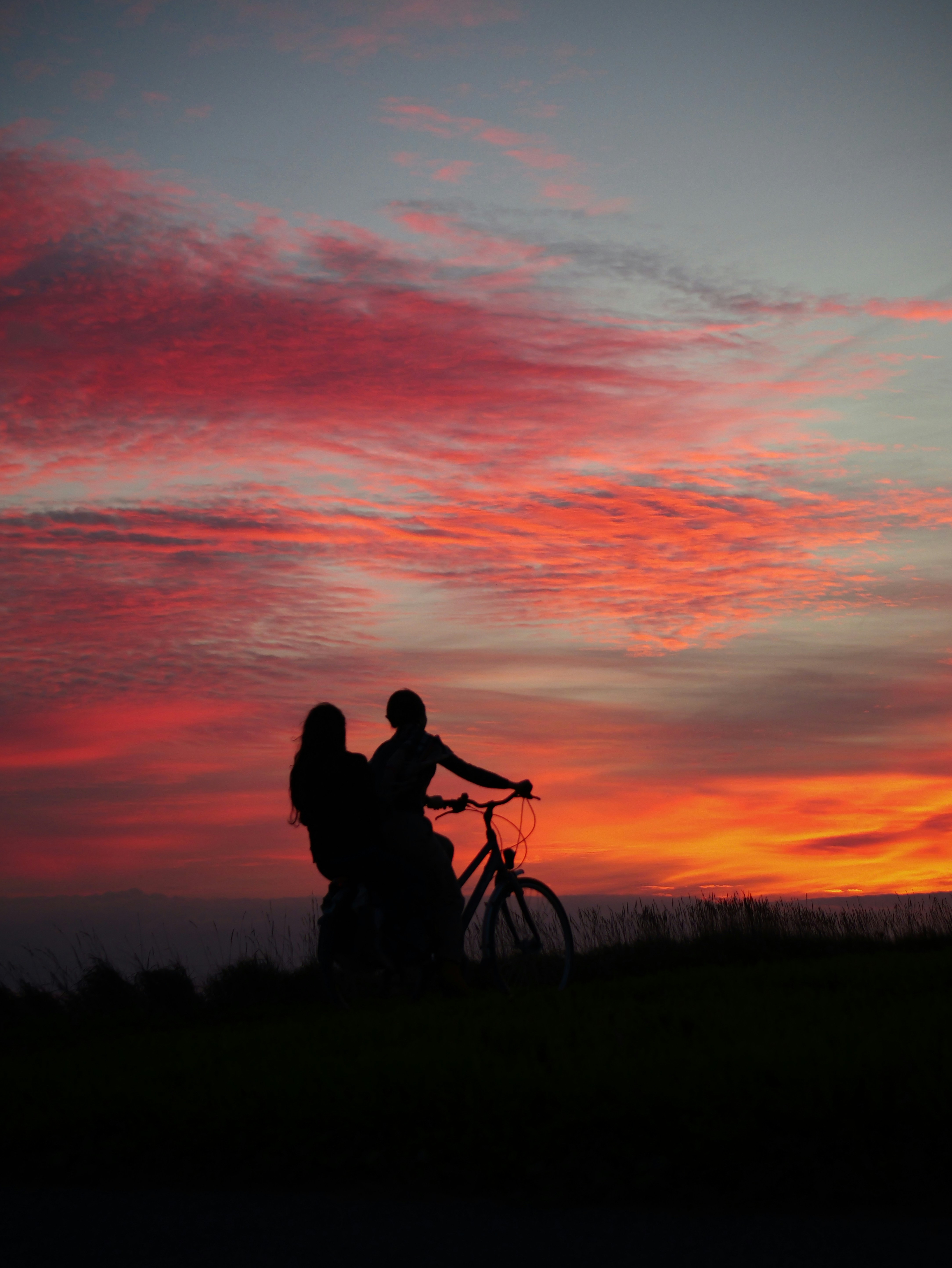 Couple faisant du vélo au coucher du soleil sous un ciel coloré