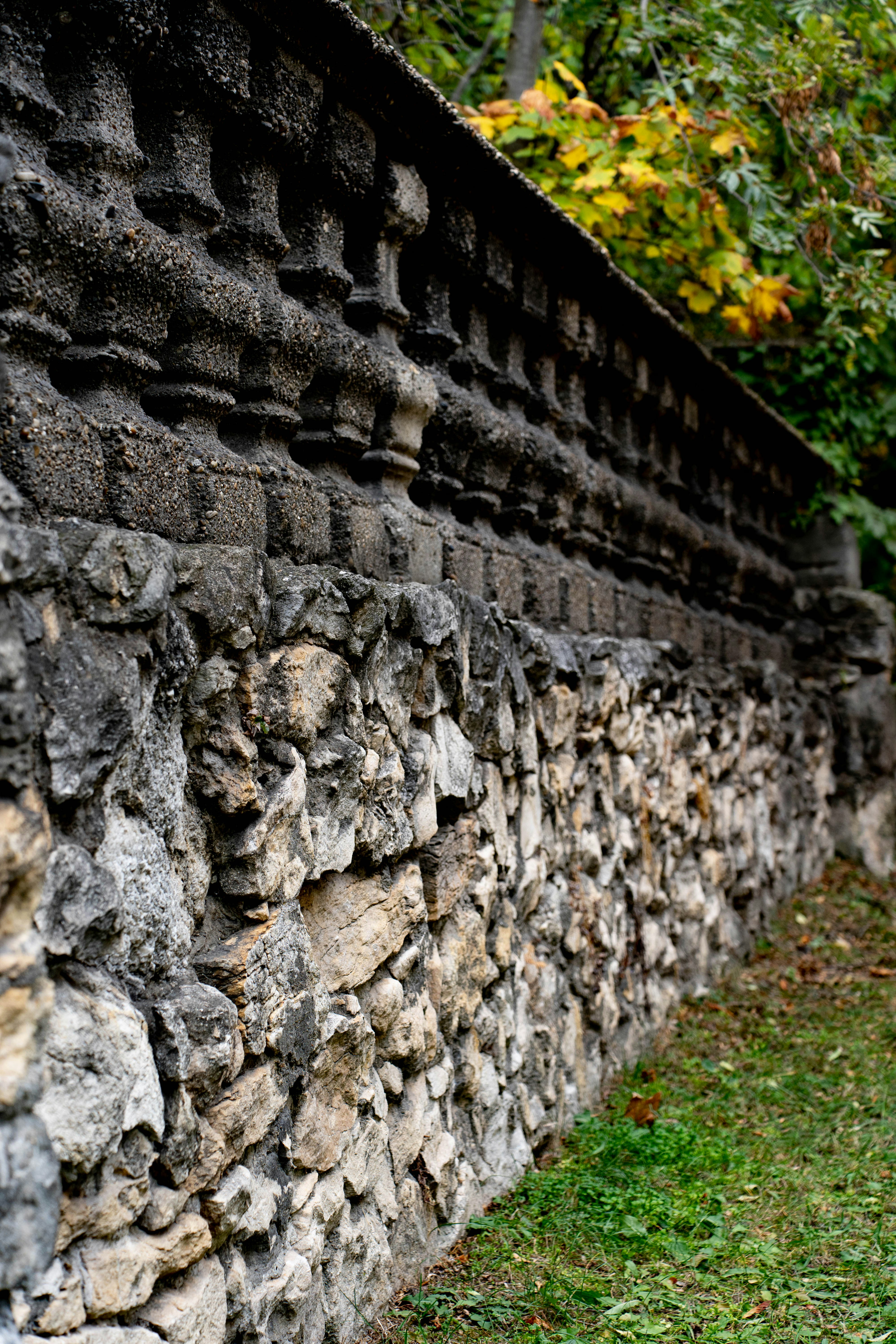 An old stone wall with decorative carvings and rough sections.