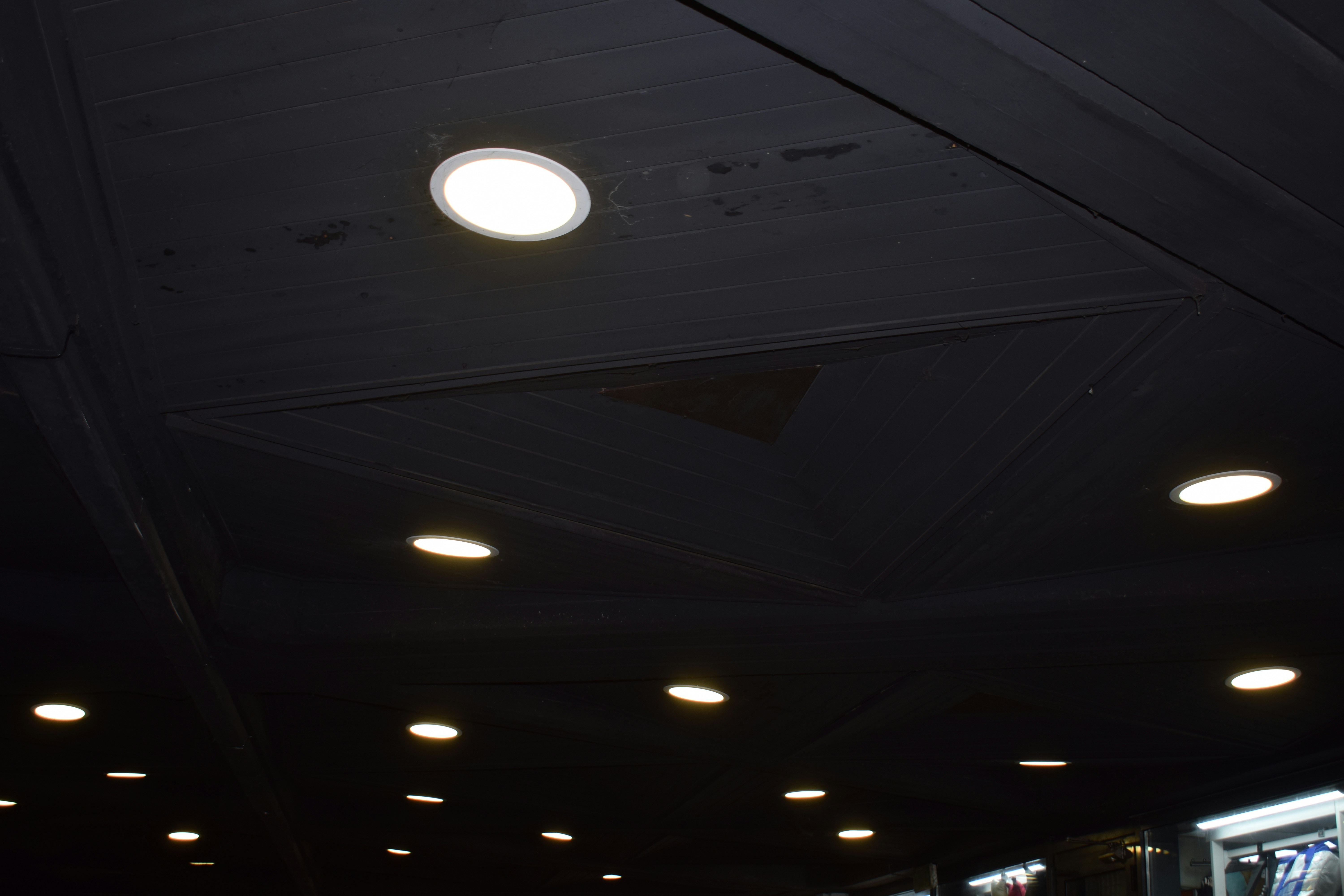 Recessed ceiling lights illuminating a dark space.