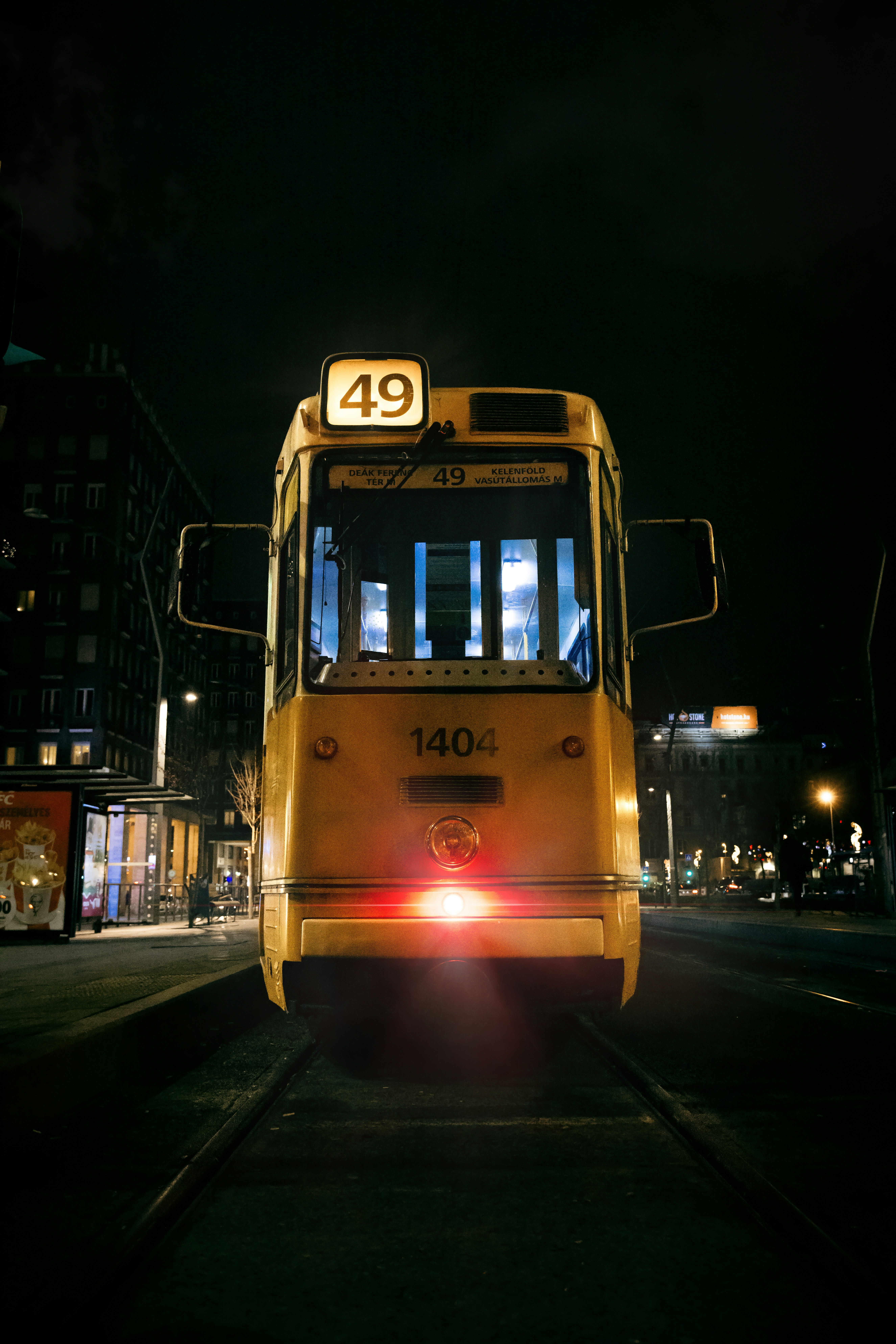 A yellow tram at night on a street