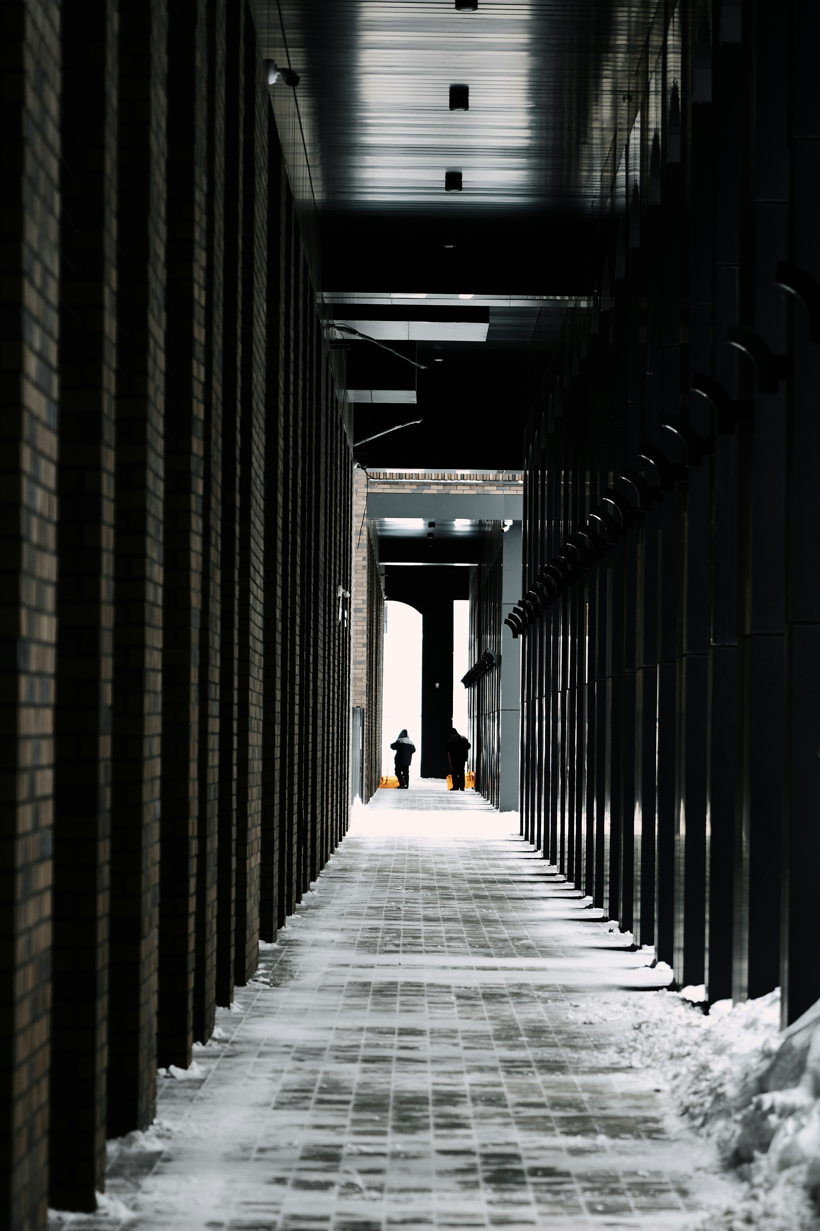 Two people walk down a snow-covered hallway.