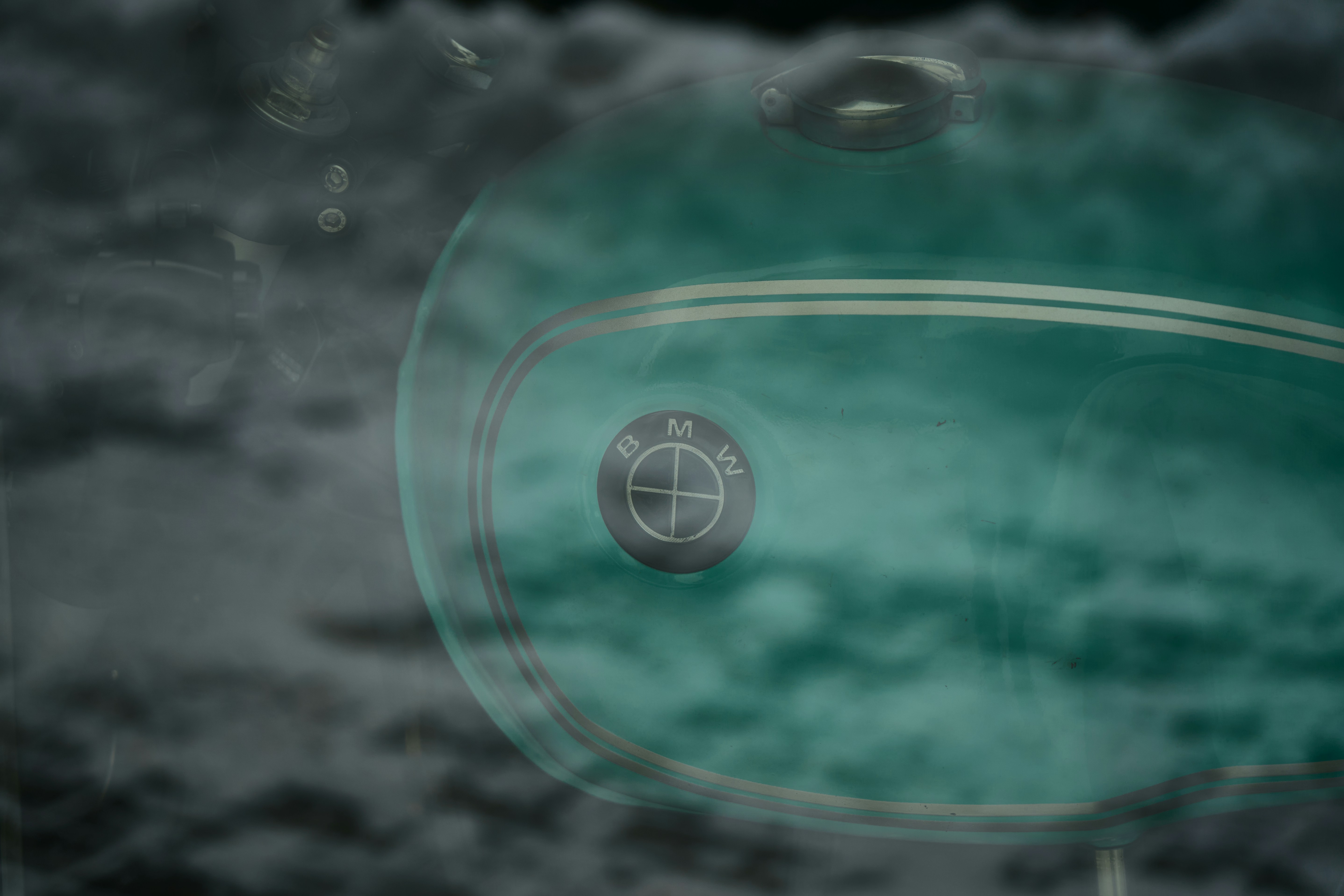 Close-up of a vintage BMW emblem on a teal background.