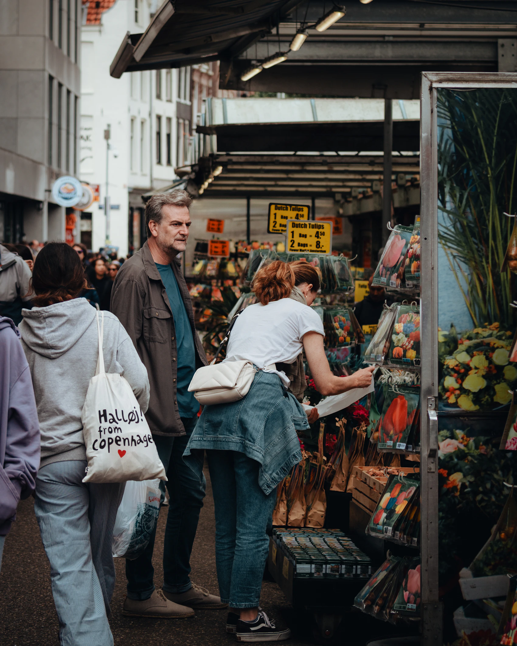 People browsing colourful flower bulbs and blooms at an Amsterdam market stall