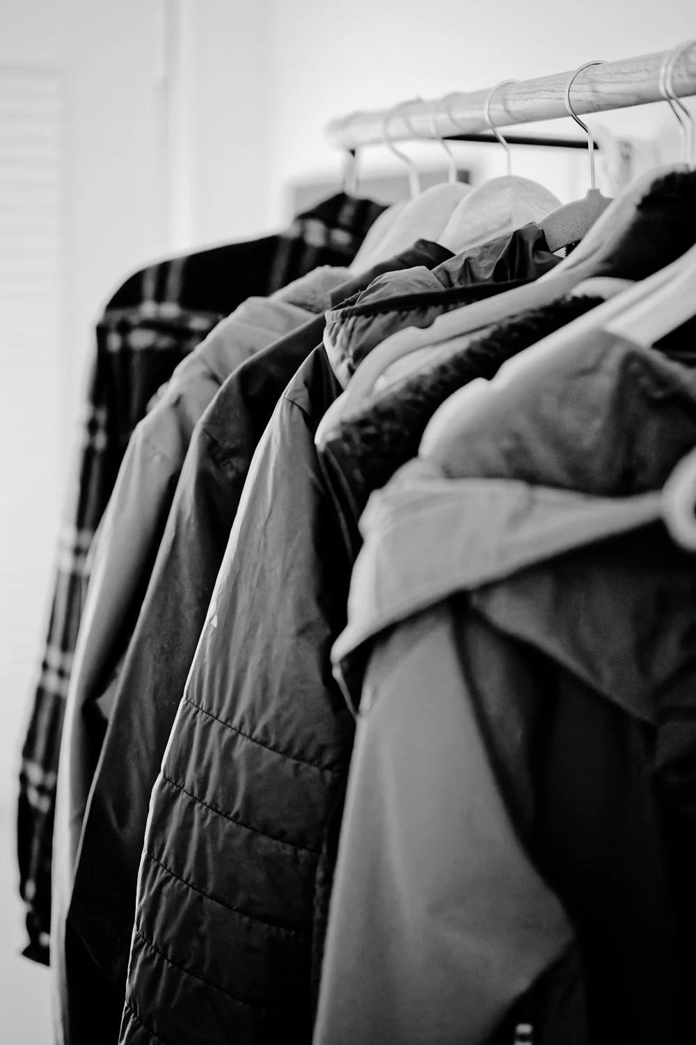 Coats and jackets on wooden hangers in a home closet
