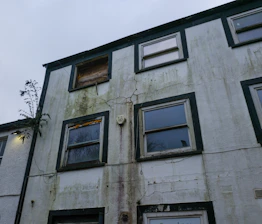 Old apartment building with weathered facade and boarded window