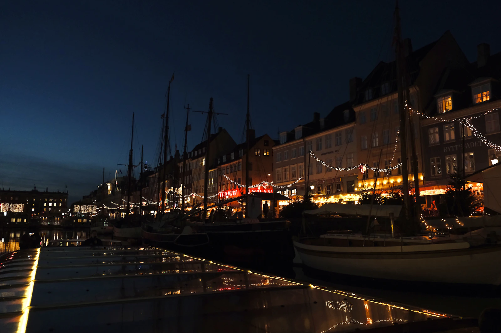 Boats and lit historic buildings reflected in Copenhagen's Nyhavn canal