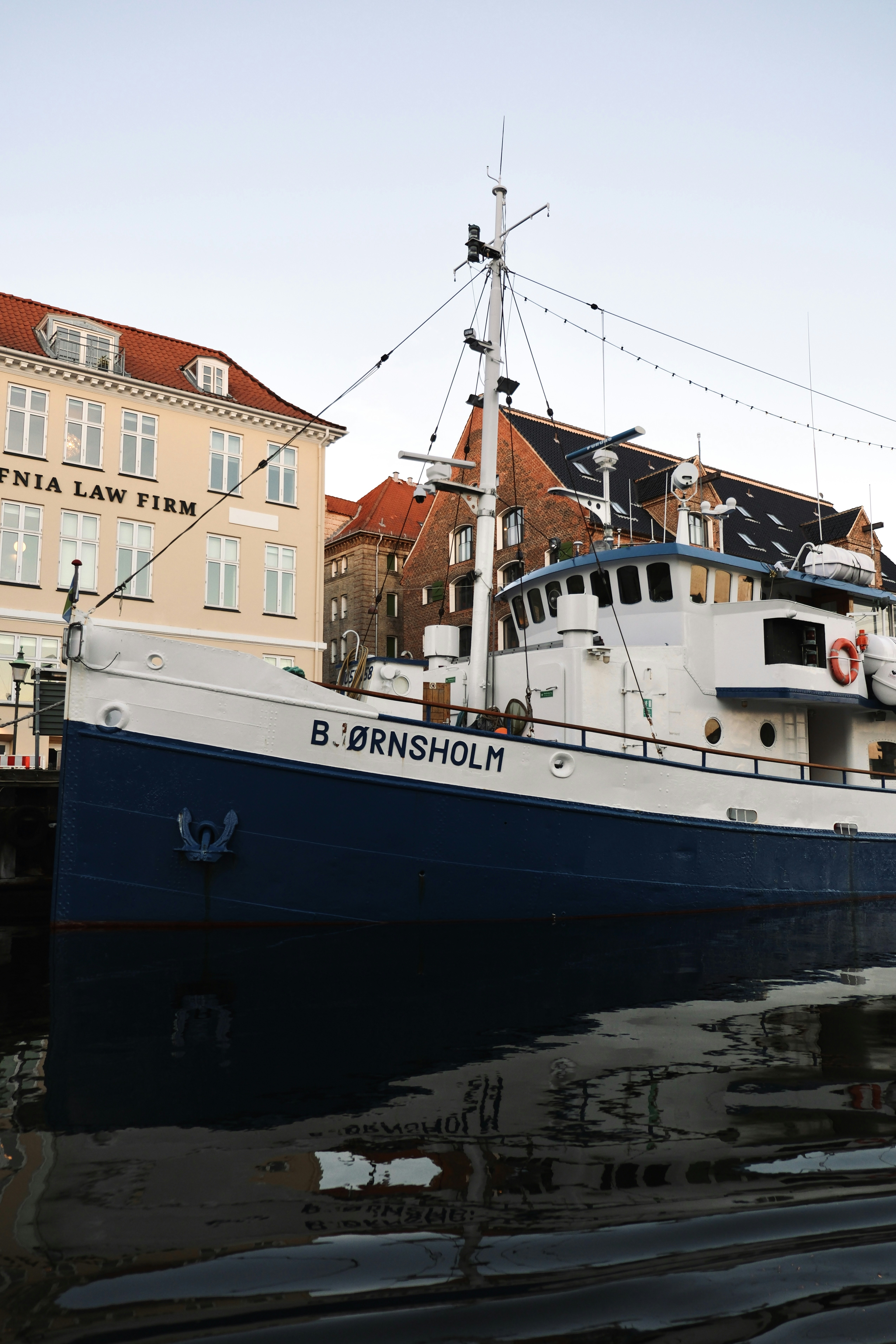 A blue and white boat docked near buildings