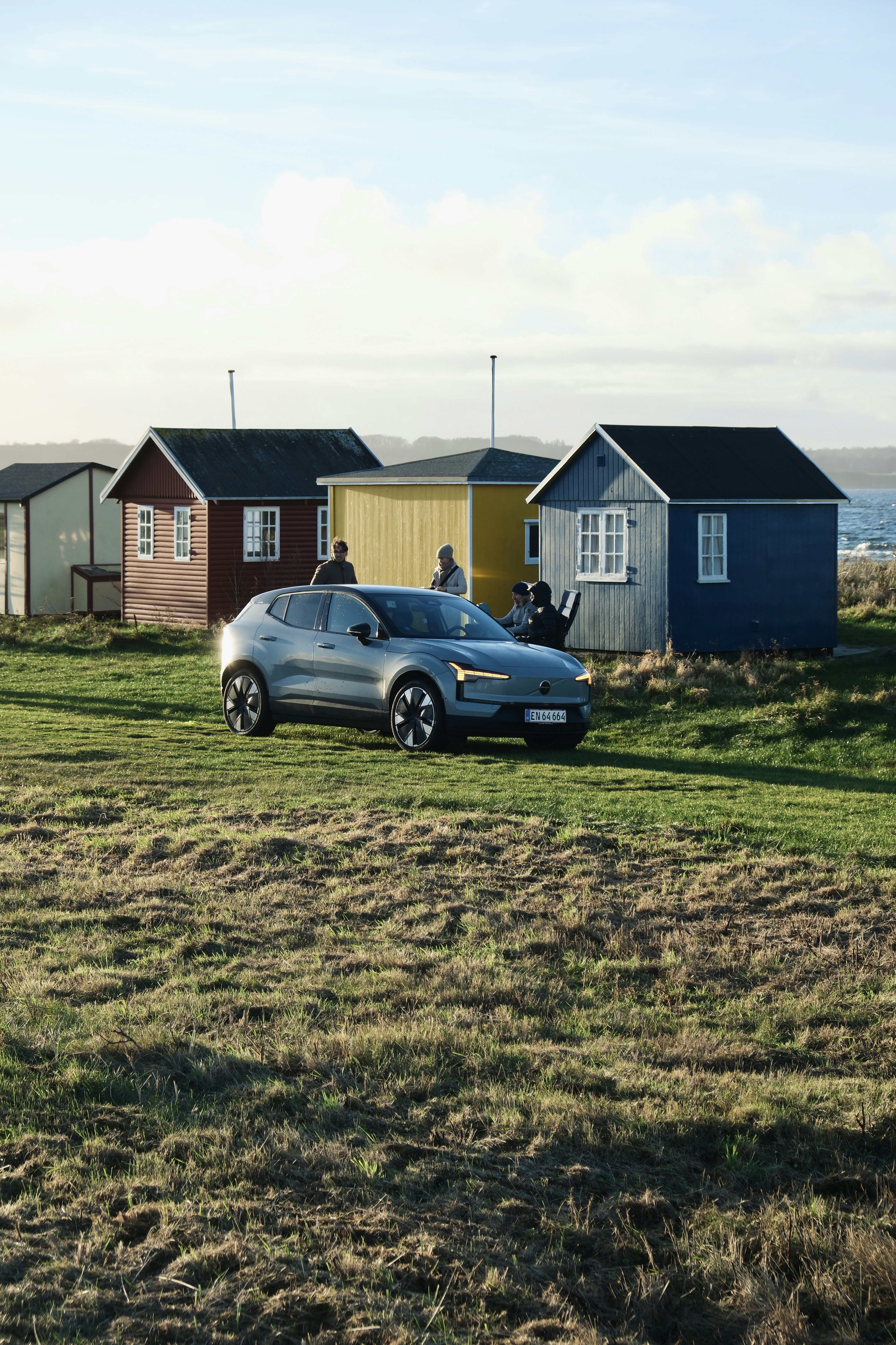 Electric car parked near colorful beach huts