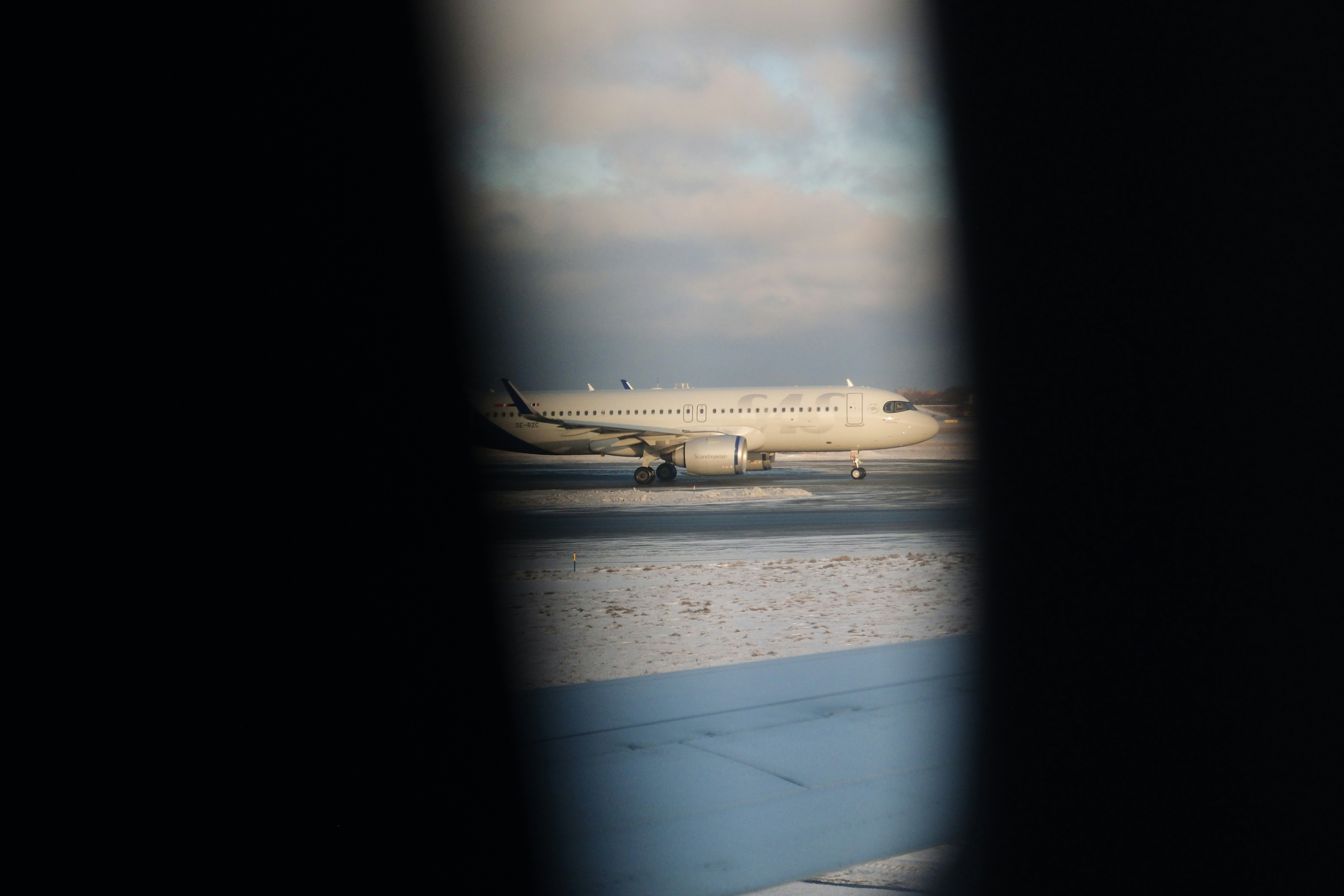 Airplane on a snowy tarmac under cloudy sky