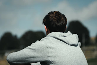 Man in grey hoodie looking out at landscape
