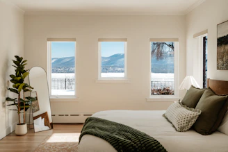 Bedroom with a view of snowy mountains through three windows