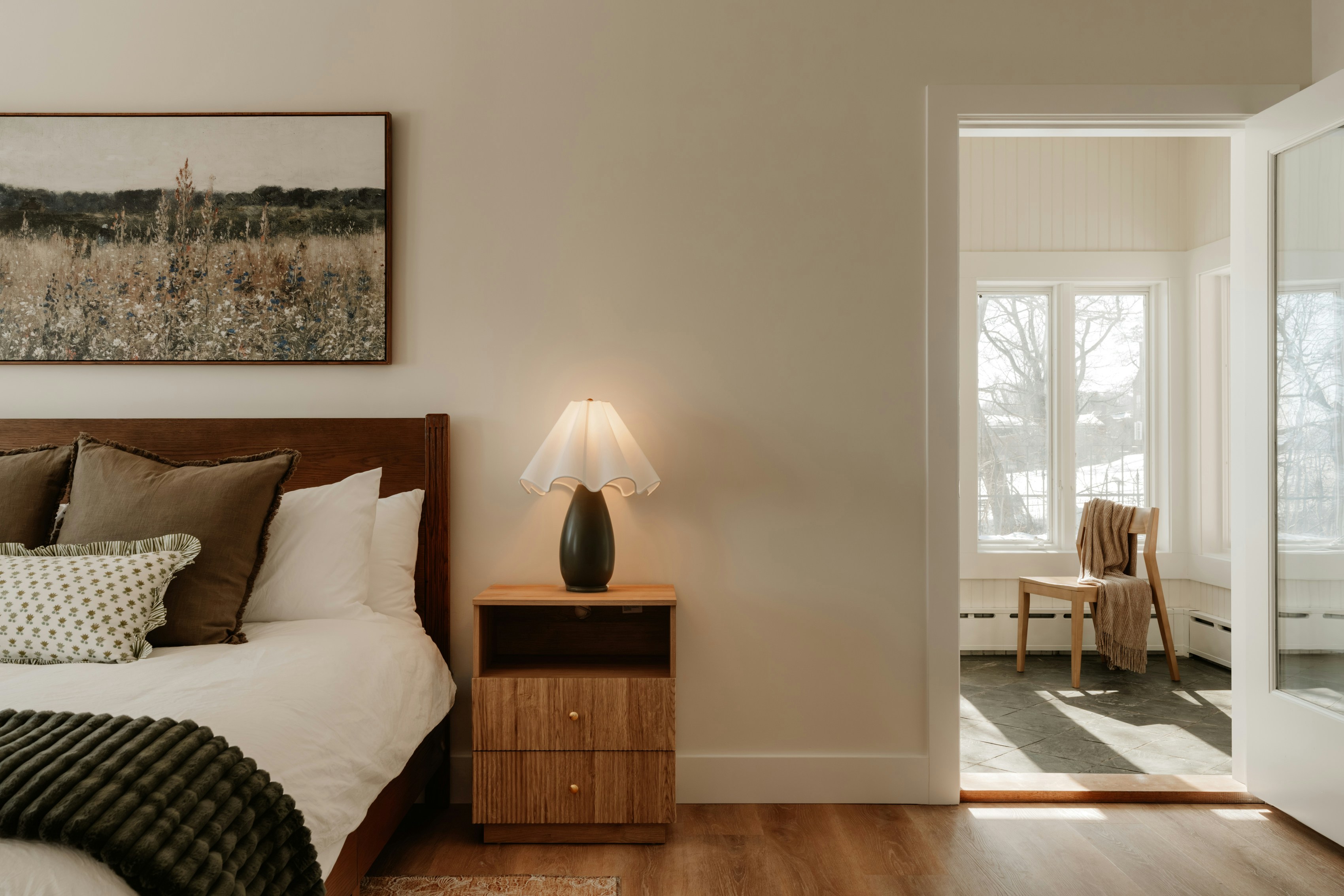 Bedroom with a wooden nightstand and a chair in doorway.