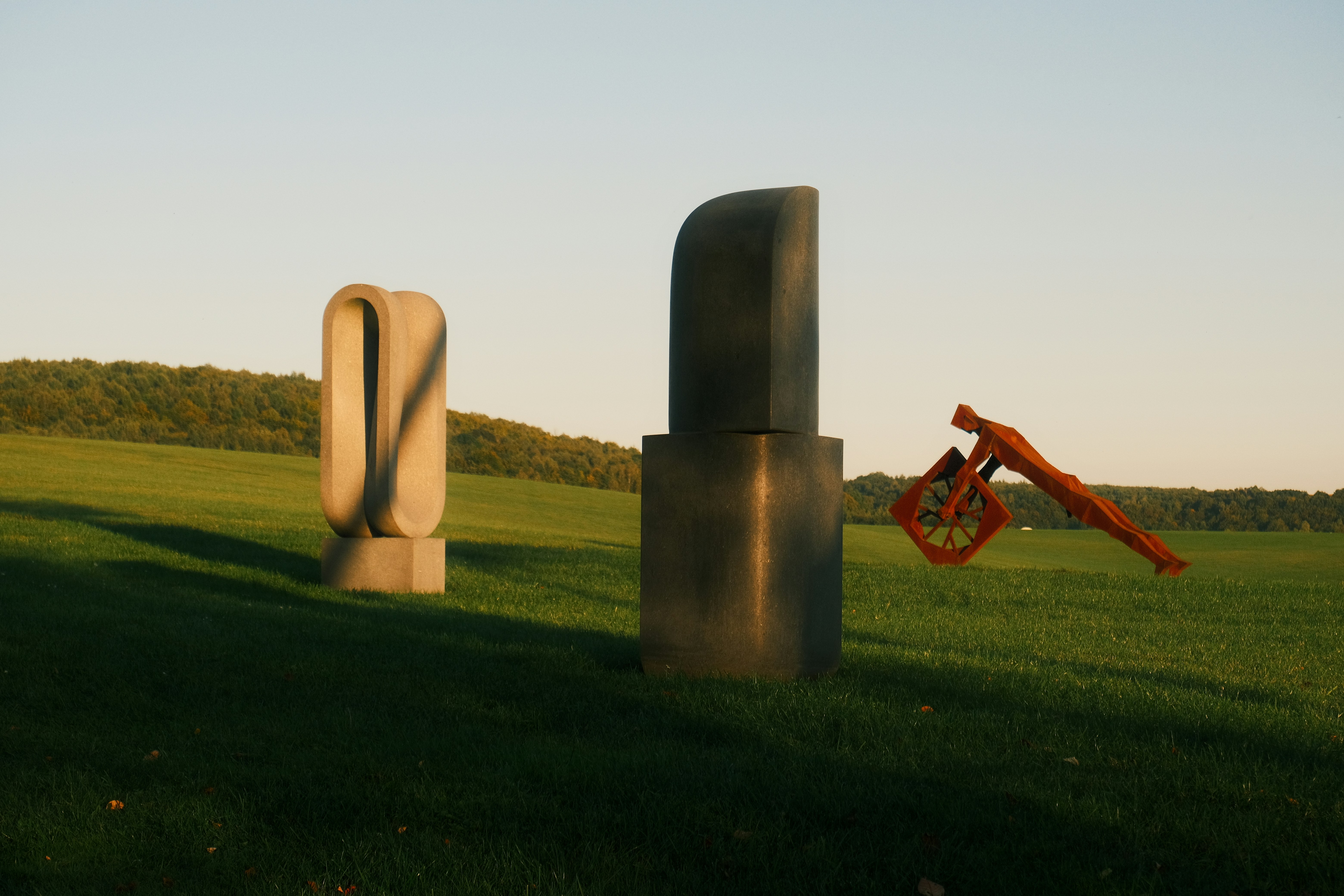 Two abstract sculptures and a cannon in a grassy field
