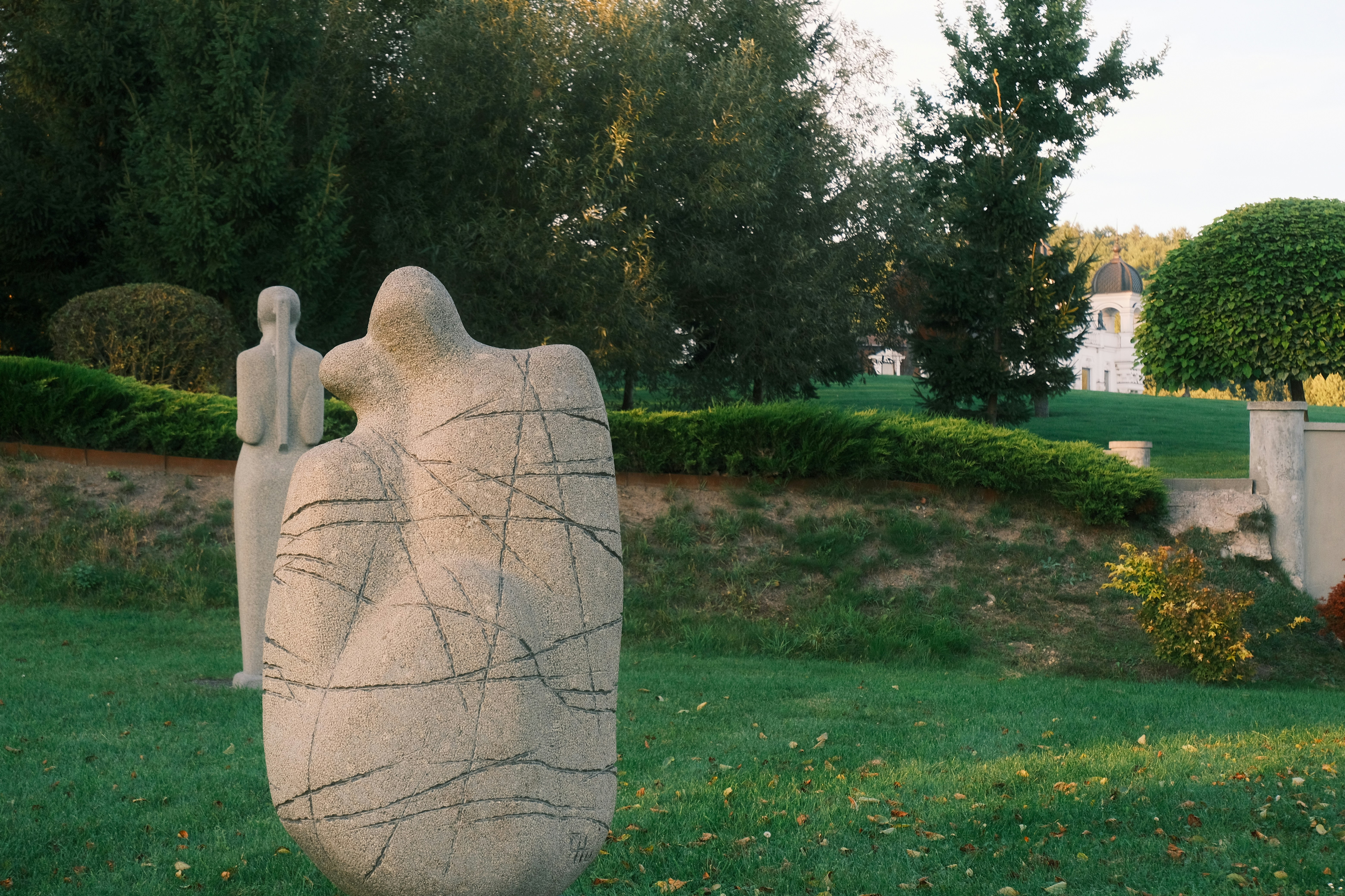 Two abstract sculptures in a grassy park setting.