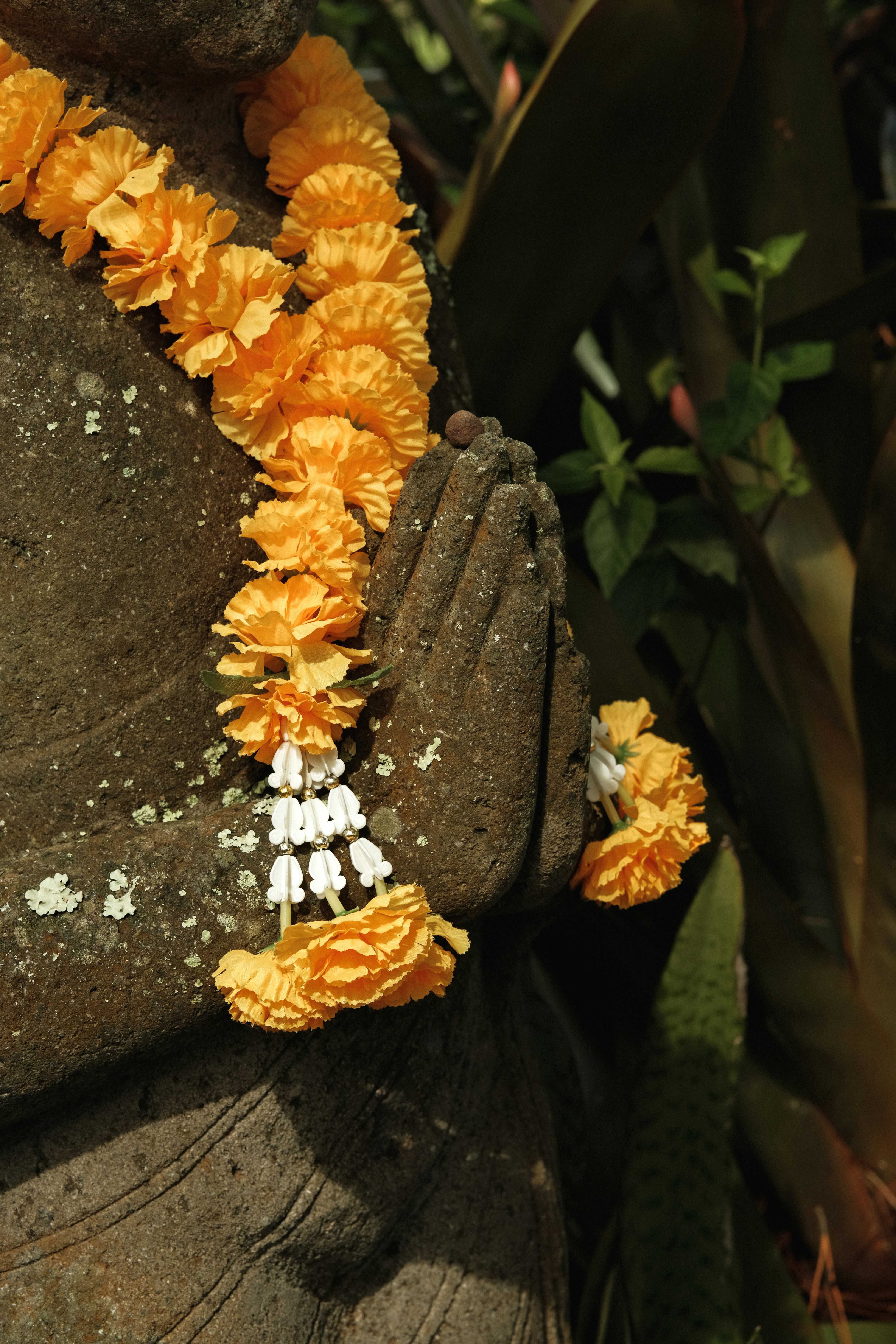 Stone hands with orange flower garland
