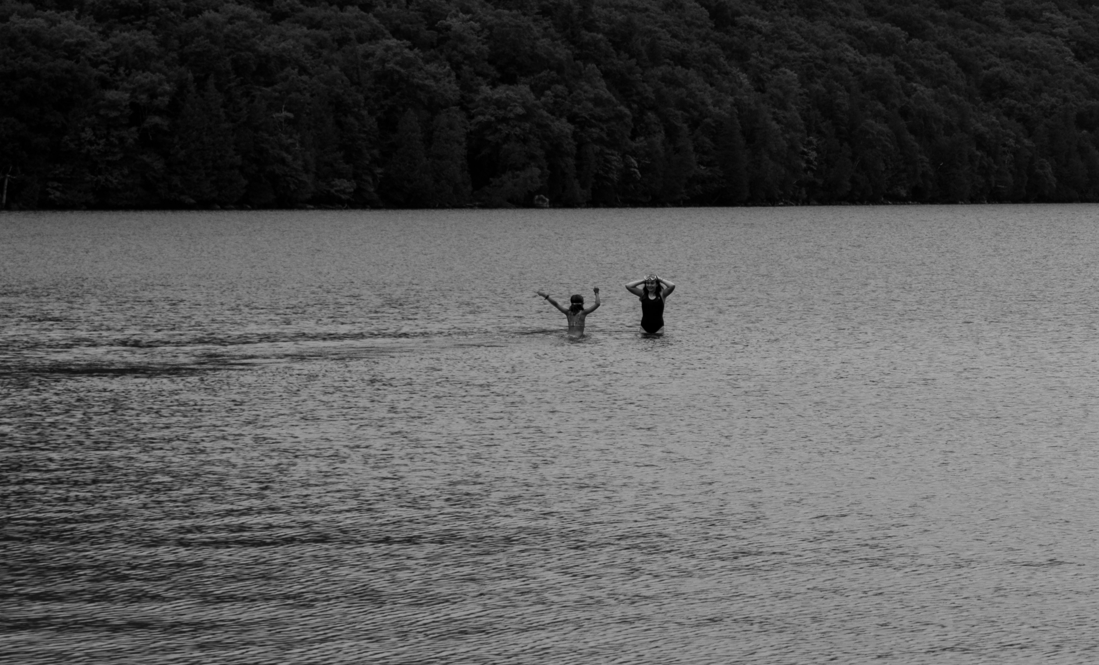 Two people wading in a calm lake