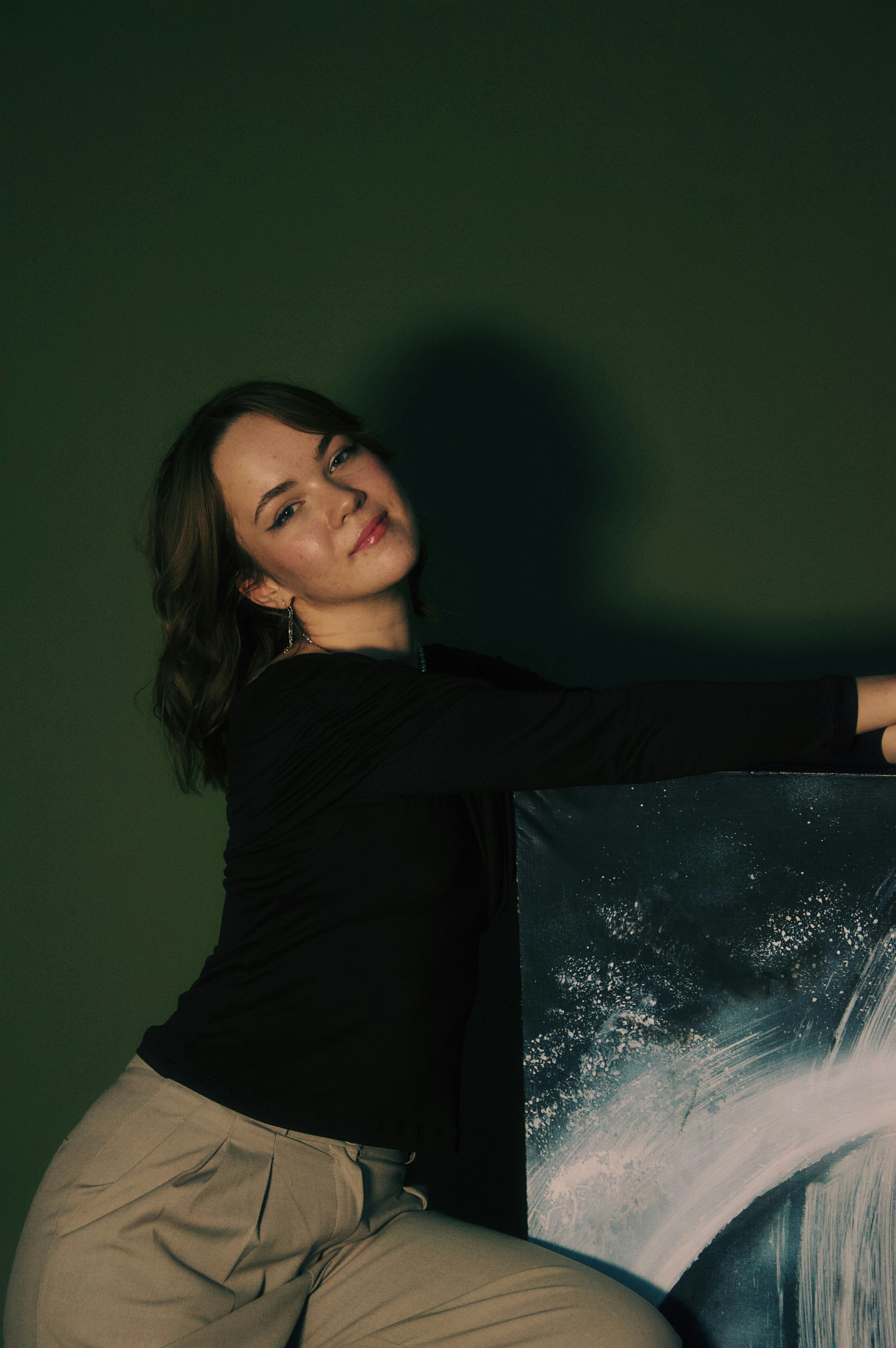 Joven posa con arte abstracto sobre fondo verde